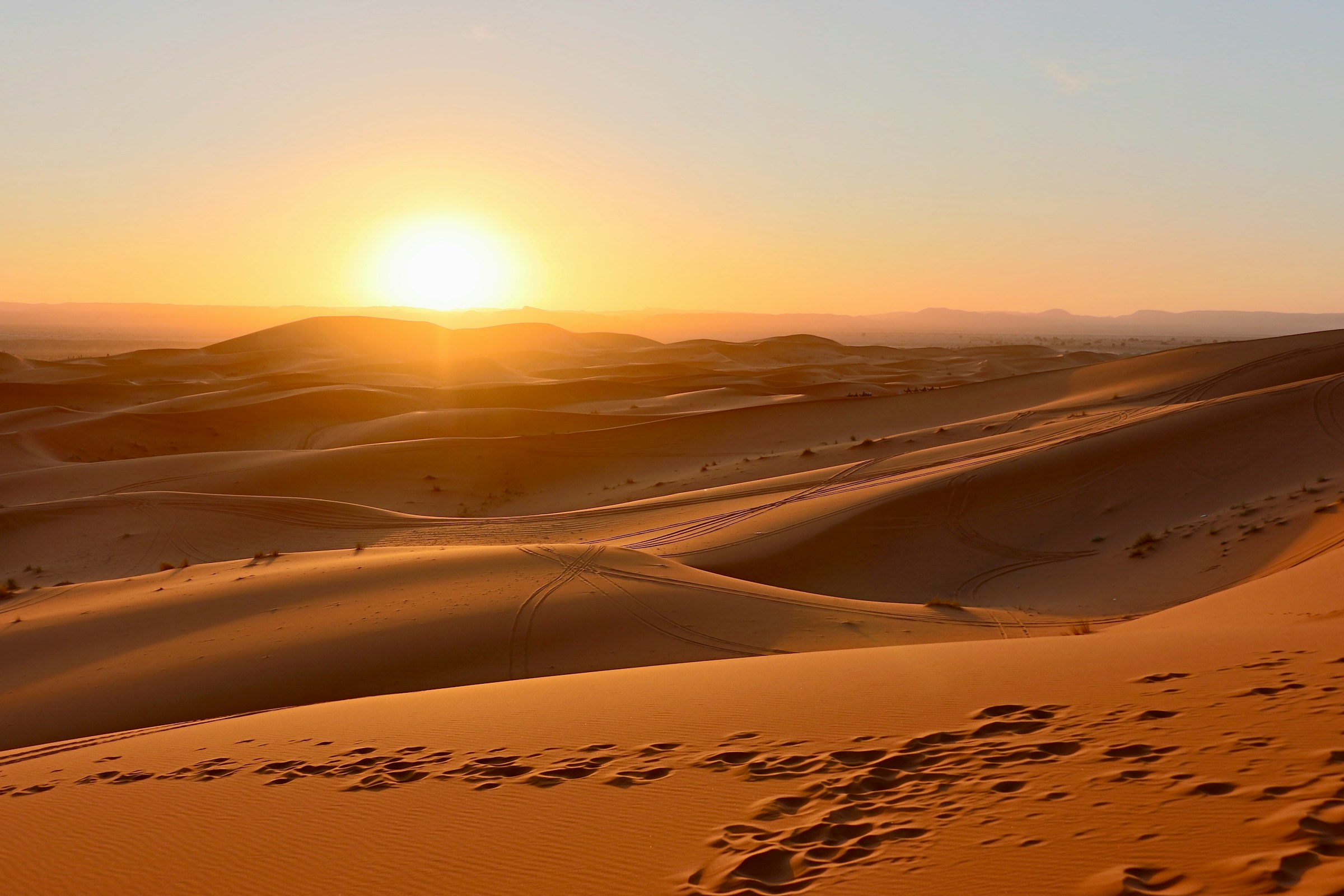 Sun setting over sweeping desert sand dunes