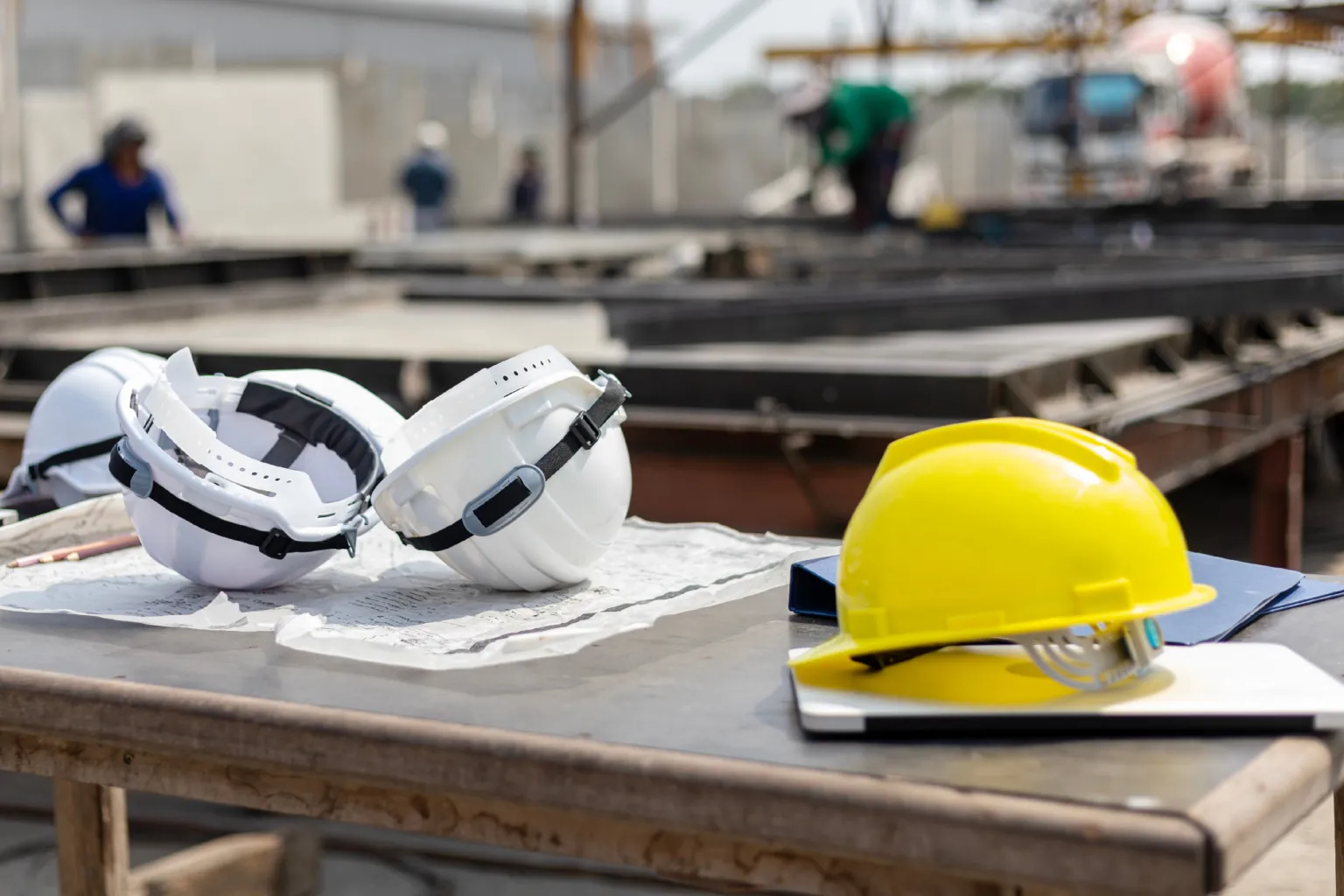 Sicherheitshelme liegen auf einem Tisch einer Baustelle, symbolisieren Arbeitsschutz im Bauwesen.