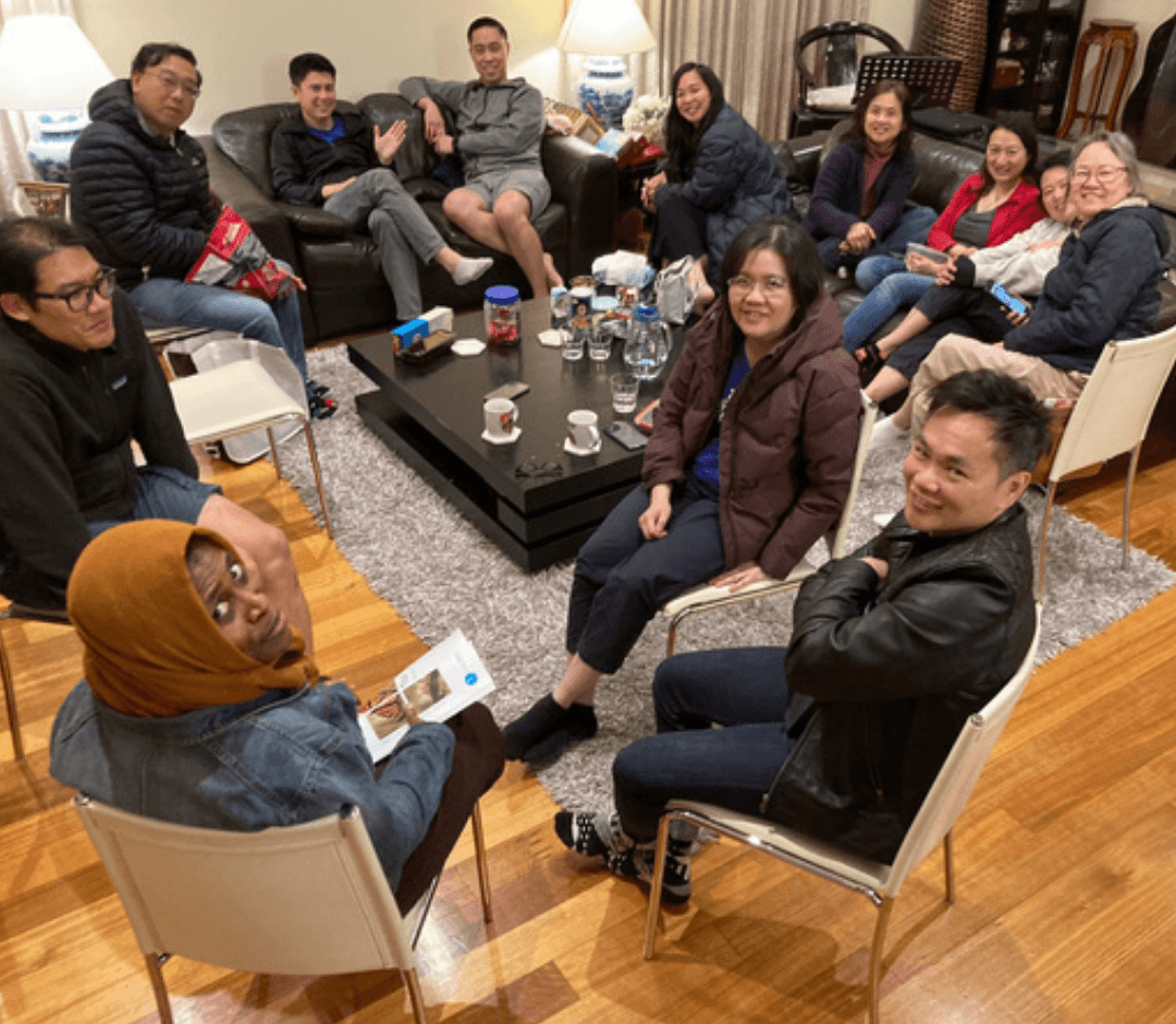 A restaurant interior featuring marble countertops, brown leather chairs, wood-paneled walls, and round pendant lights hanging above a bar set with wine glasses.