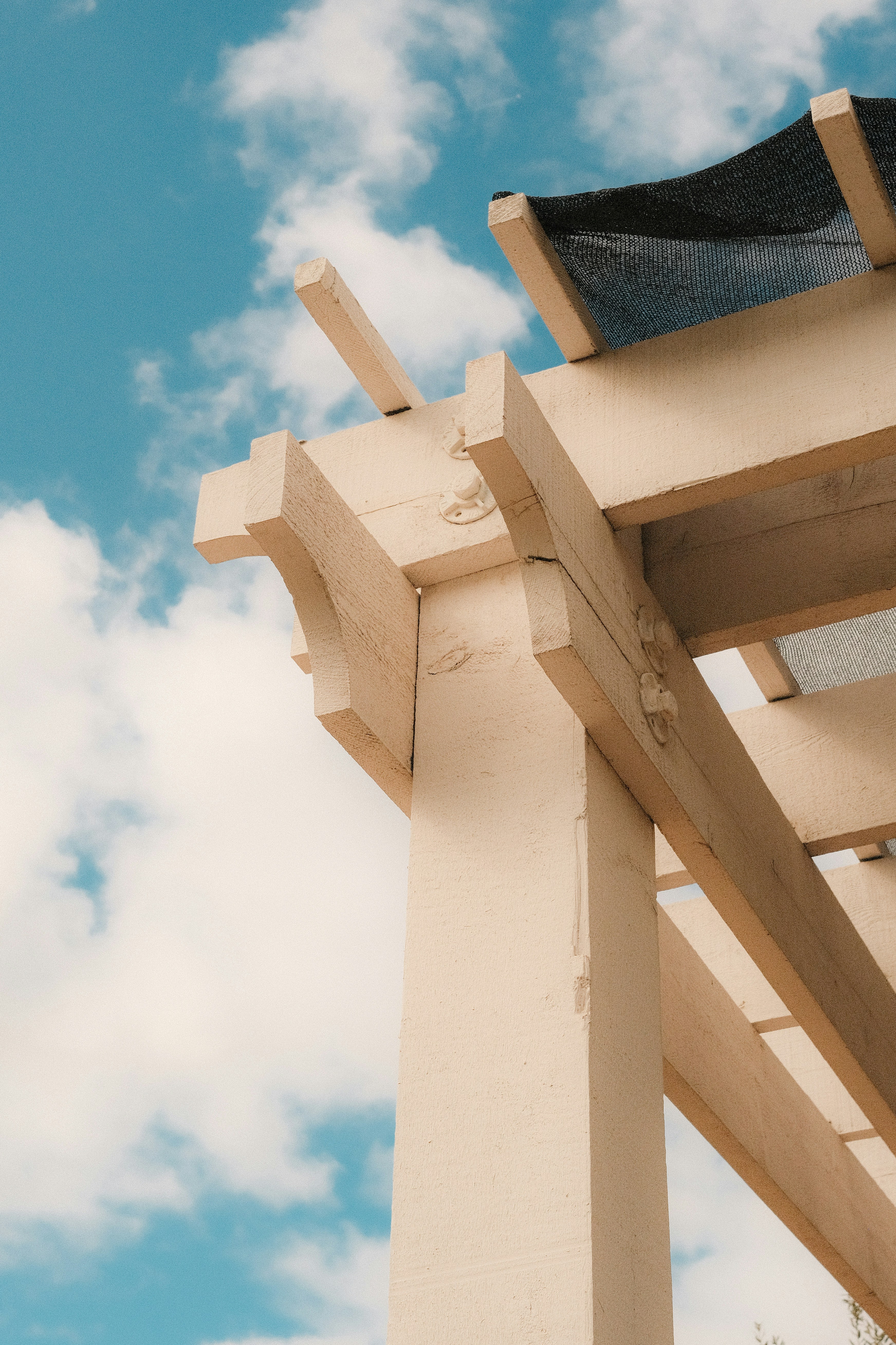 Close-up of a wooden pergola against a blue sky.