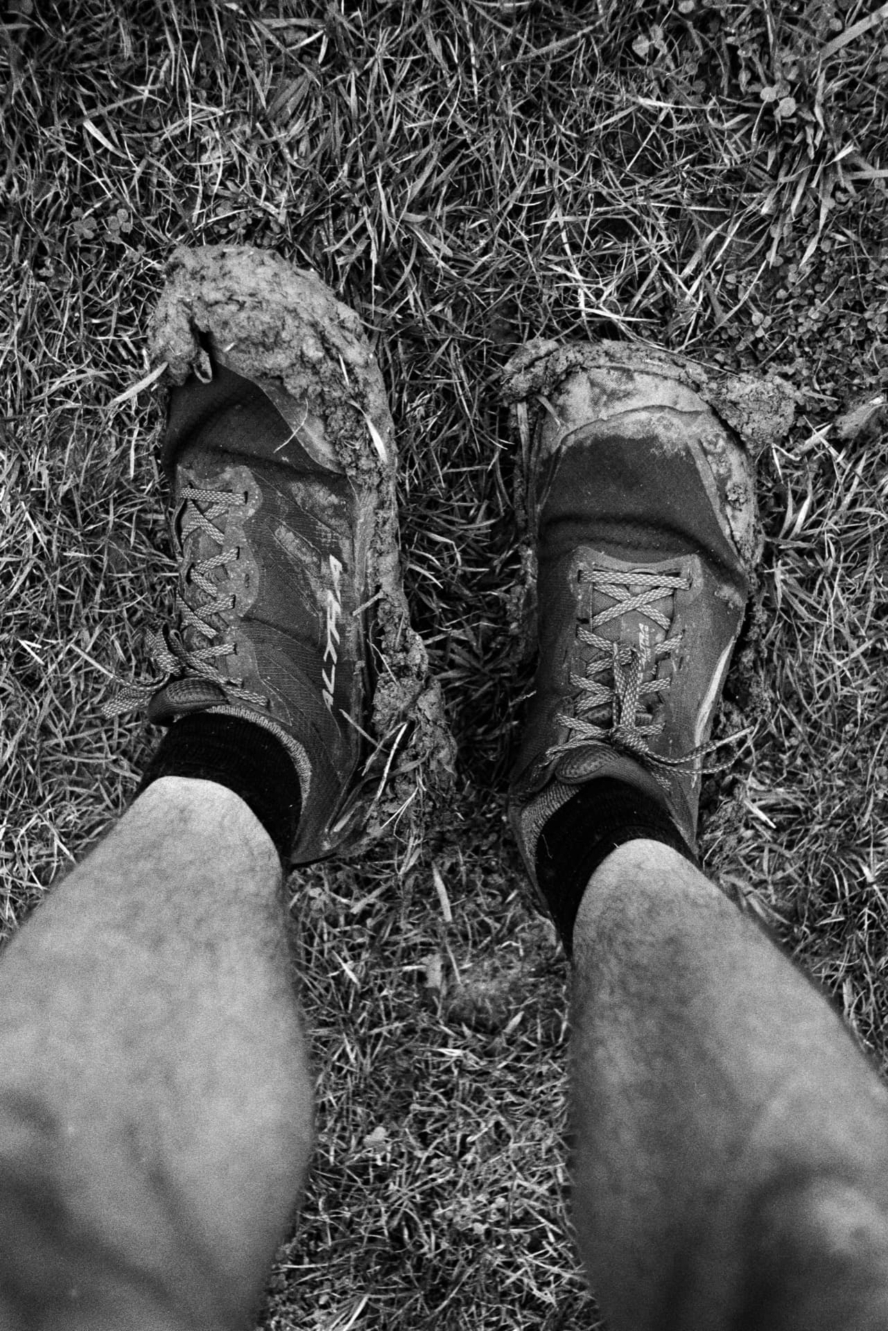 Mud-covered shoes on grass viewed from above after walking