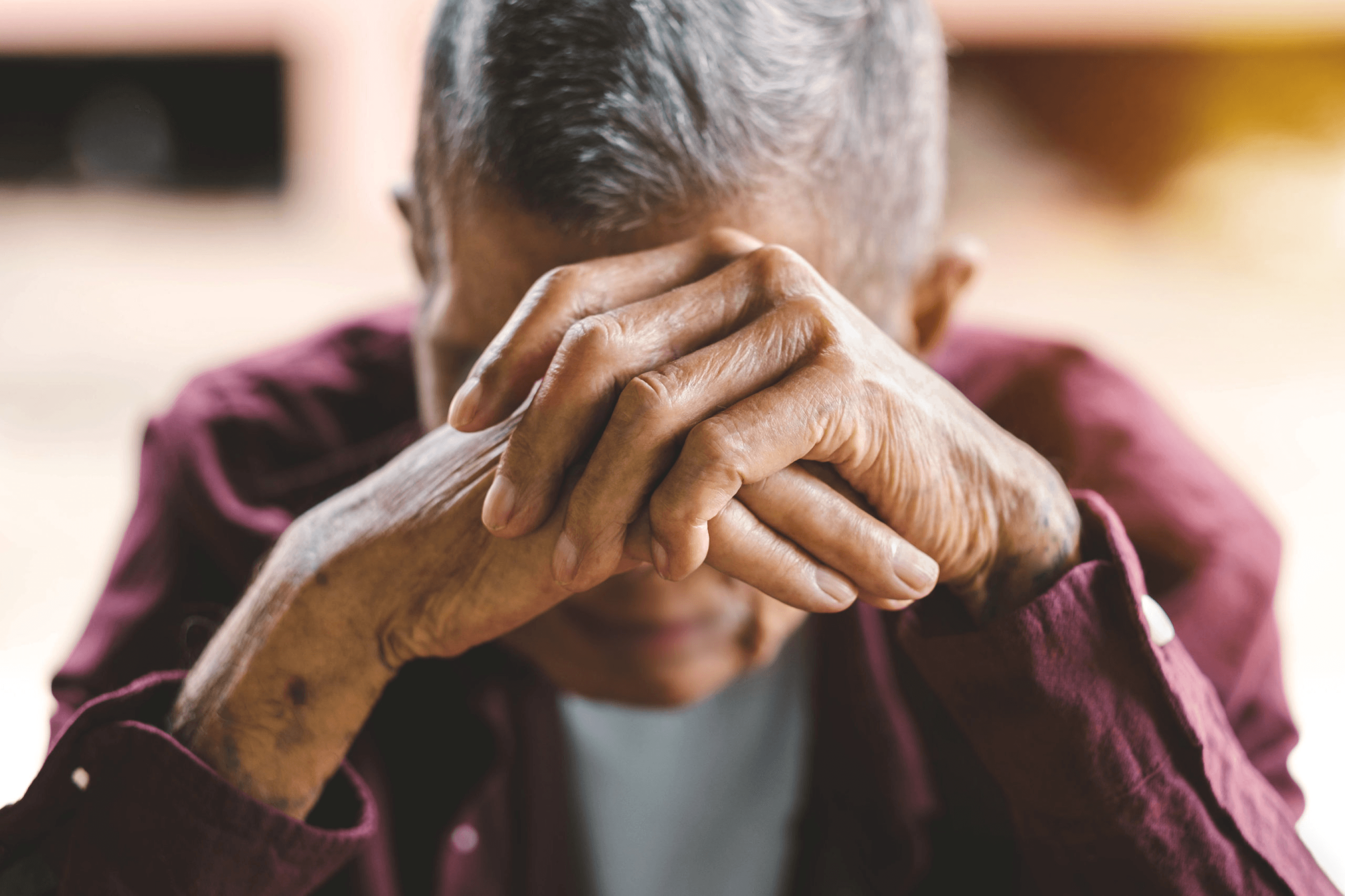 Senior man with hands clasped, symbolizing aging and health issues