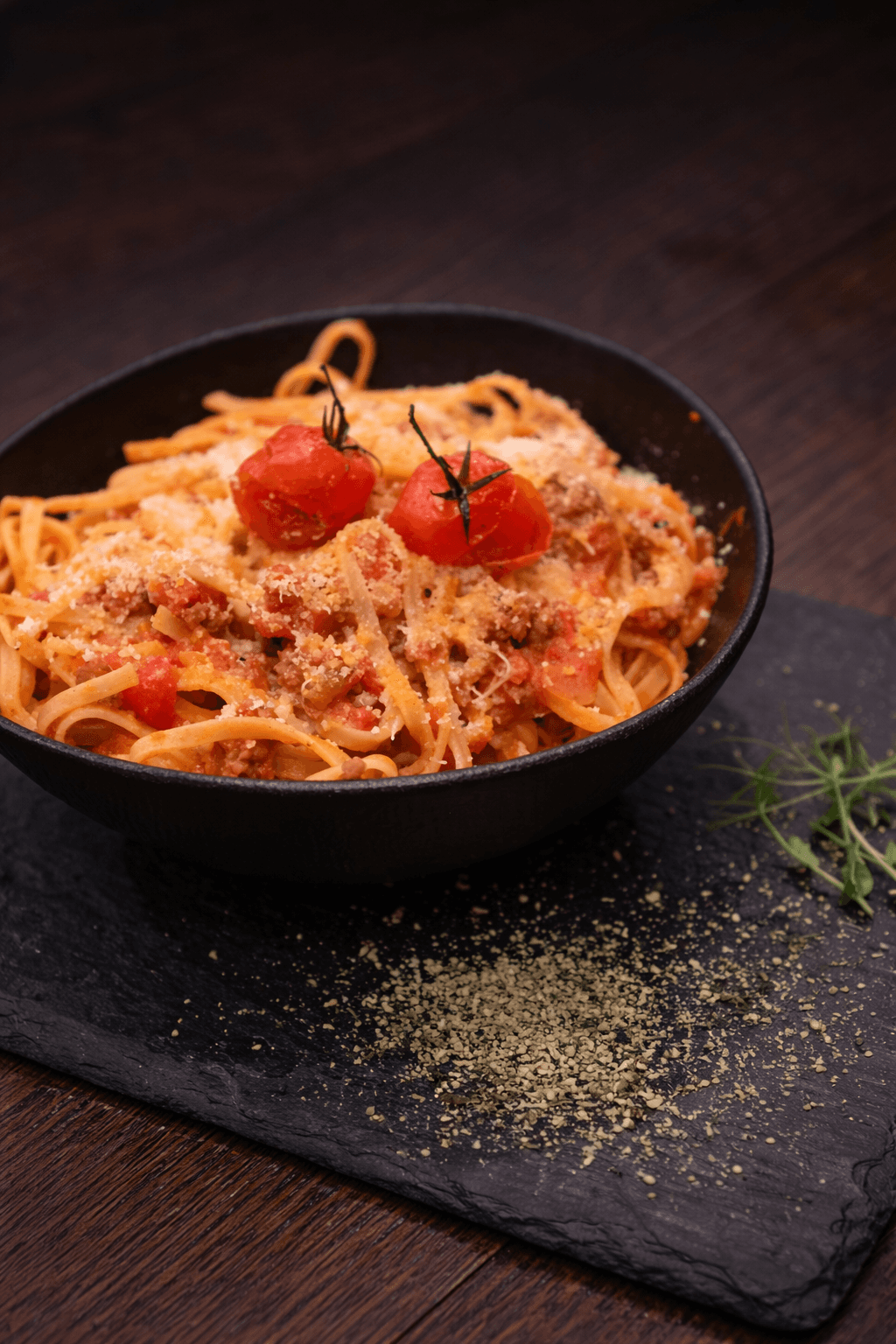 Overhead view of a kAlps Foodbar table spread with burgers, crispy fries, fondue dishes, a red cocktail, dipping sauces, and fresh garnishes arranged on slate serving boards.