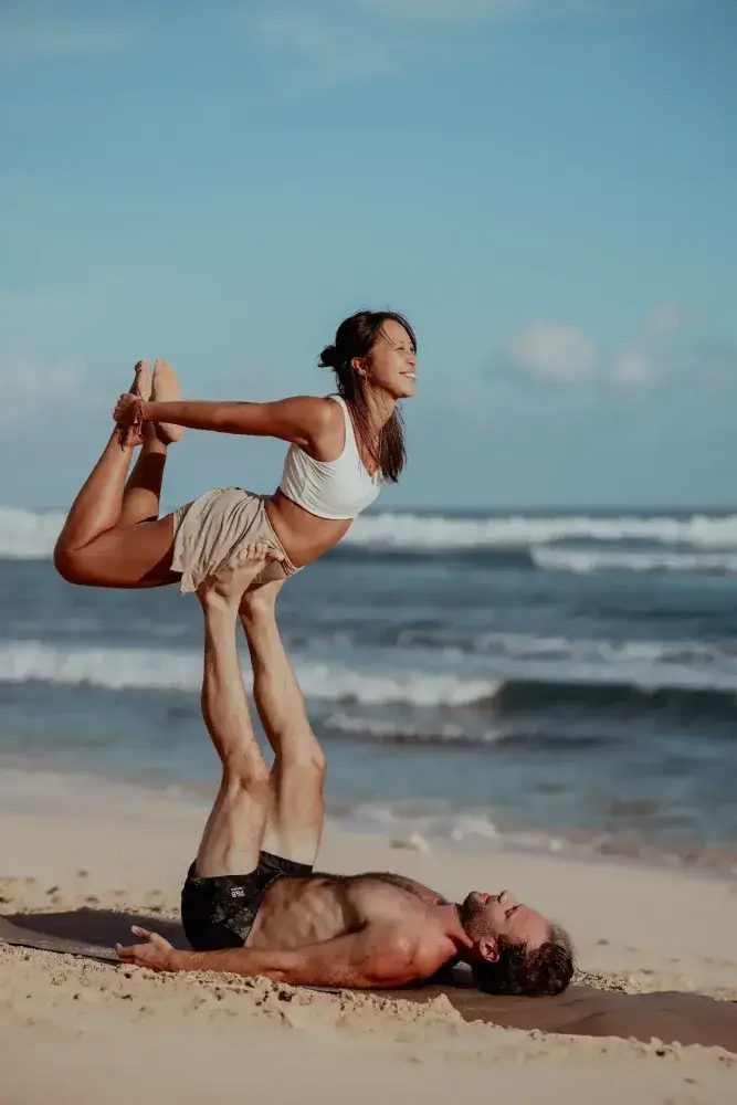 Students practicing Acro yoga on the beach during the multi-style yoga teacher training in Bali