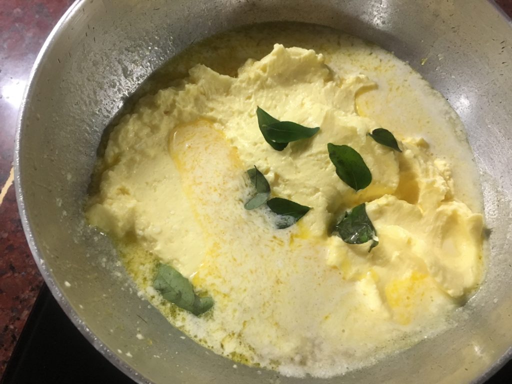 Butter getting heated in a kadhai with curry leaves
