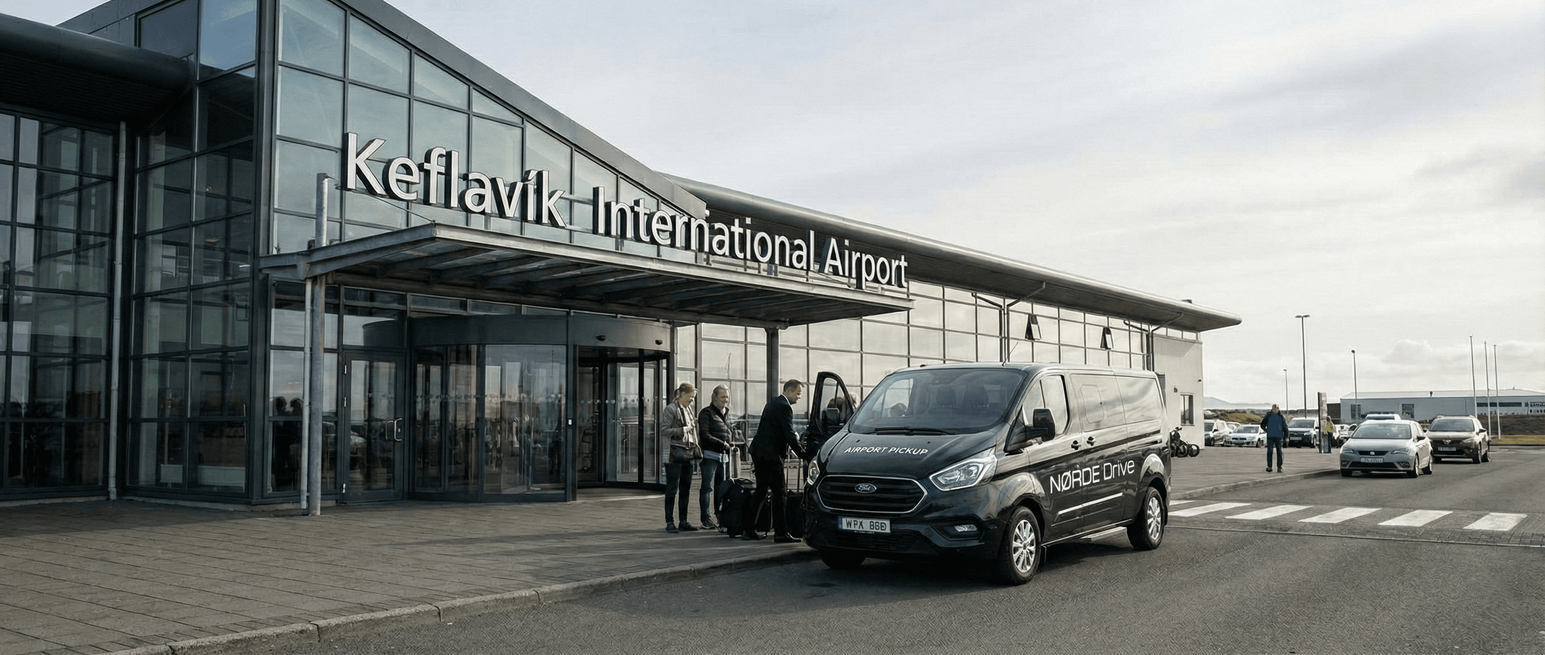 Black van parked outside the glass facade of Keflavik International Airport with people loading luggage.