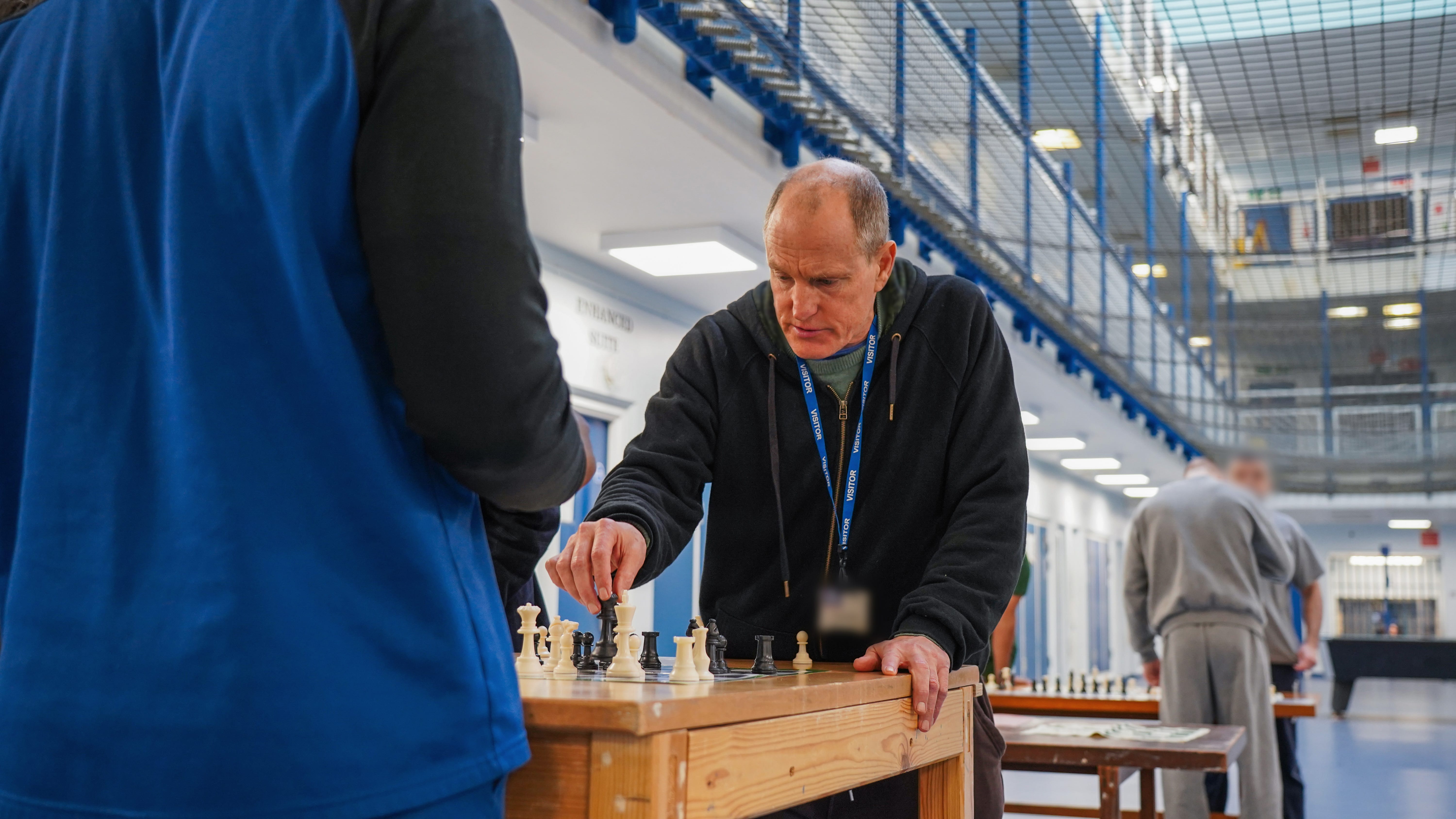Actor Woody Harrelson moves a board on a chess piece in a prison