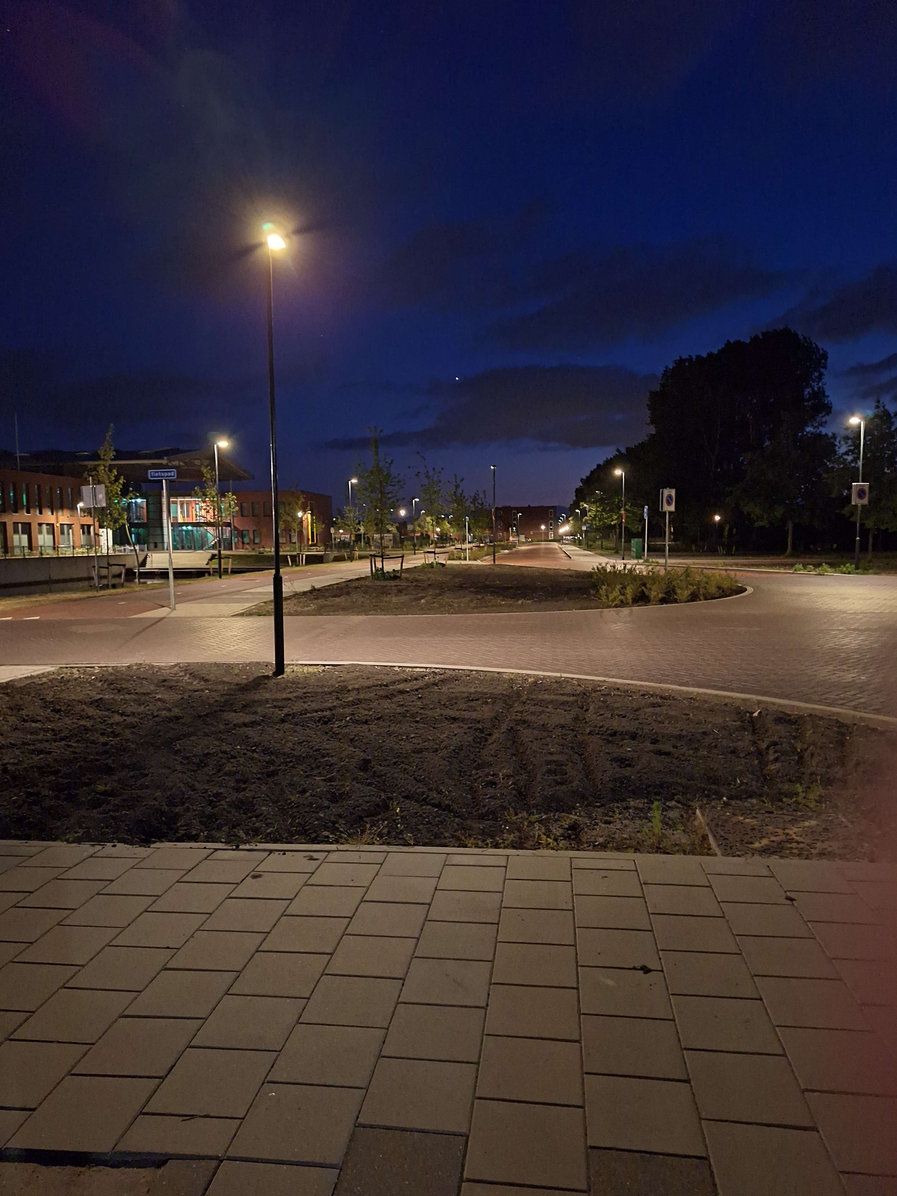 Close-up of a yellow tennis ball sitting on a green court, positioned near the white center line.