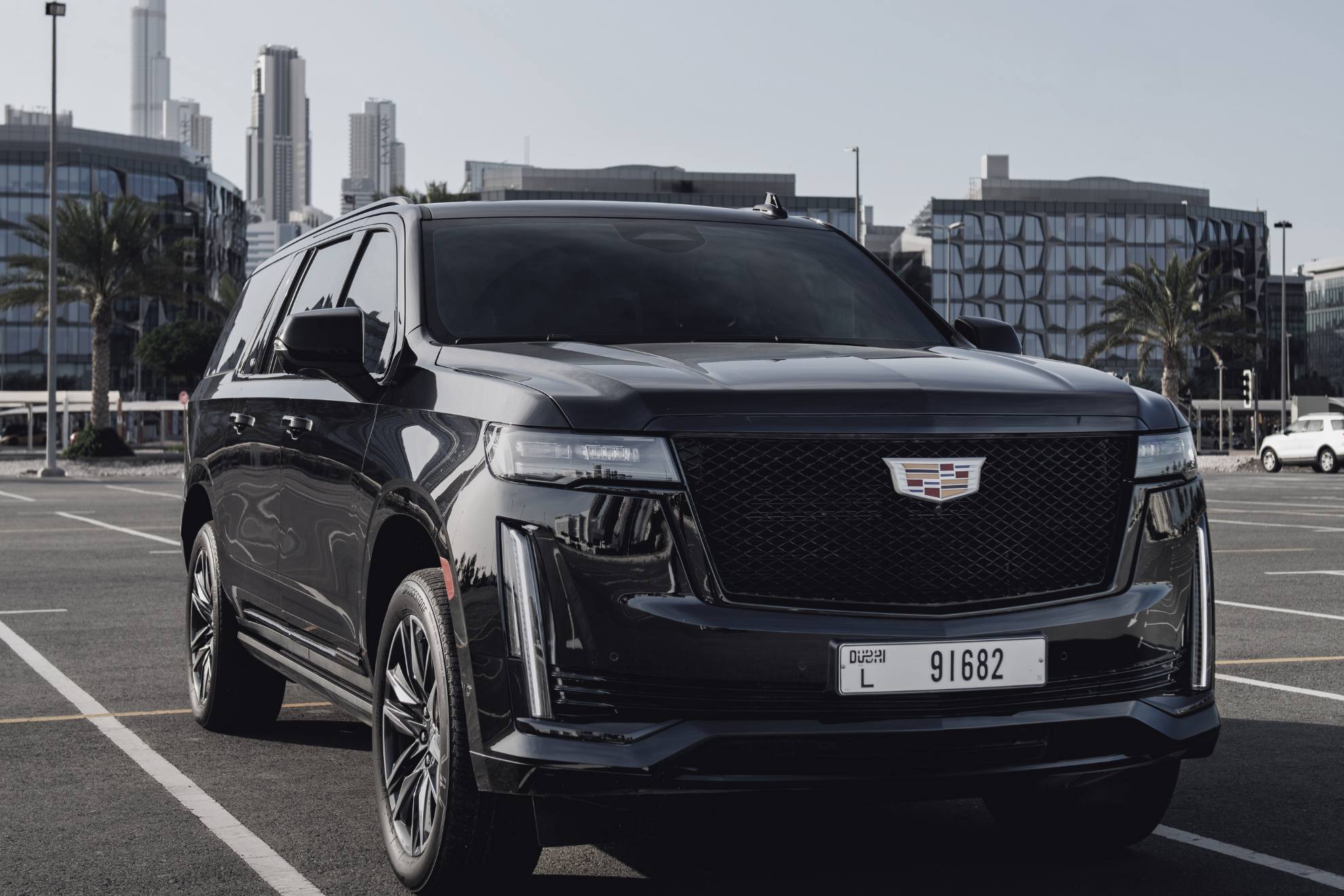 black cadillac escalade in a parking lot with burj khalifa in the background