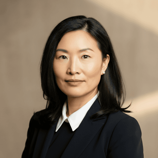 A confident Asian woman with dark hair and a pearl earring, wearing a navy suit and white shirt, embodying professional.