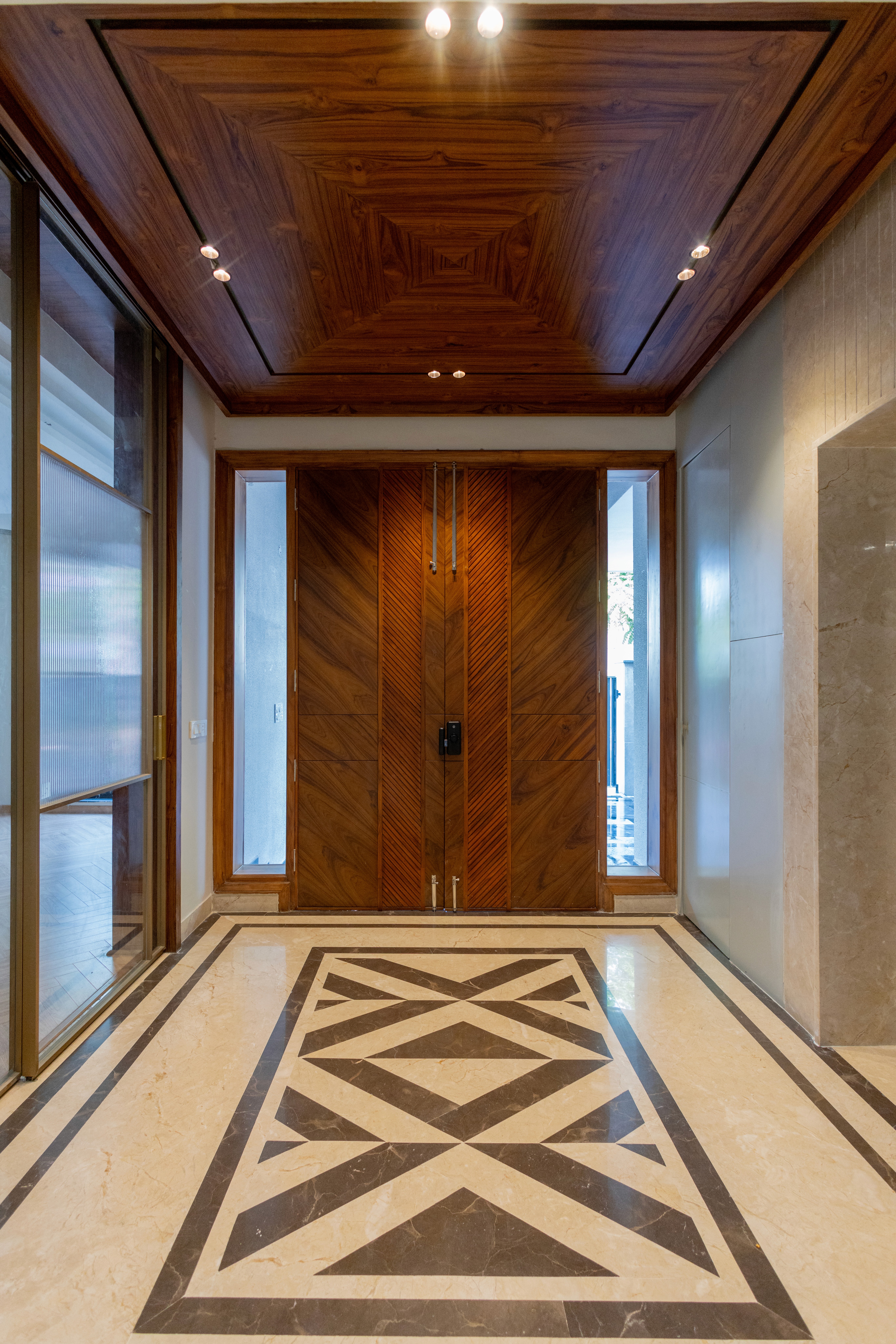 Minimalist living space featuring oak flooring, timber wall panels and panoramic windows with natural light.
