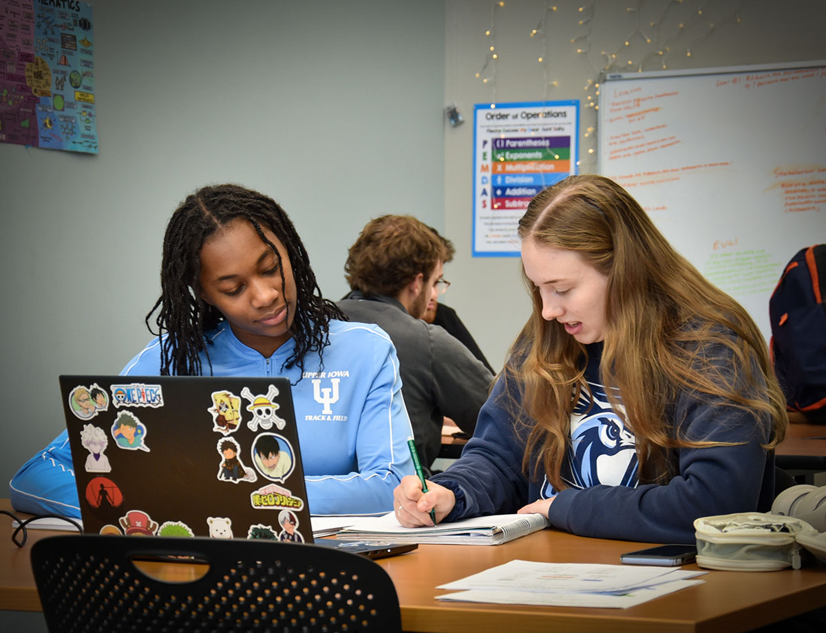 Two UIU students study together at a large desk