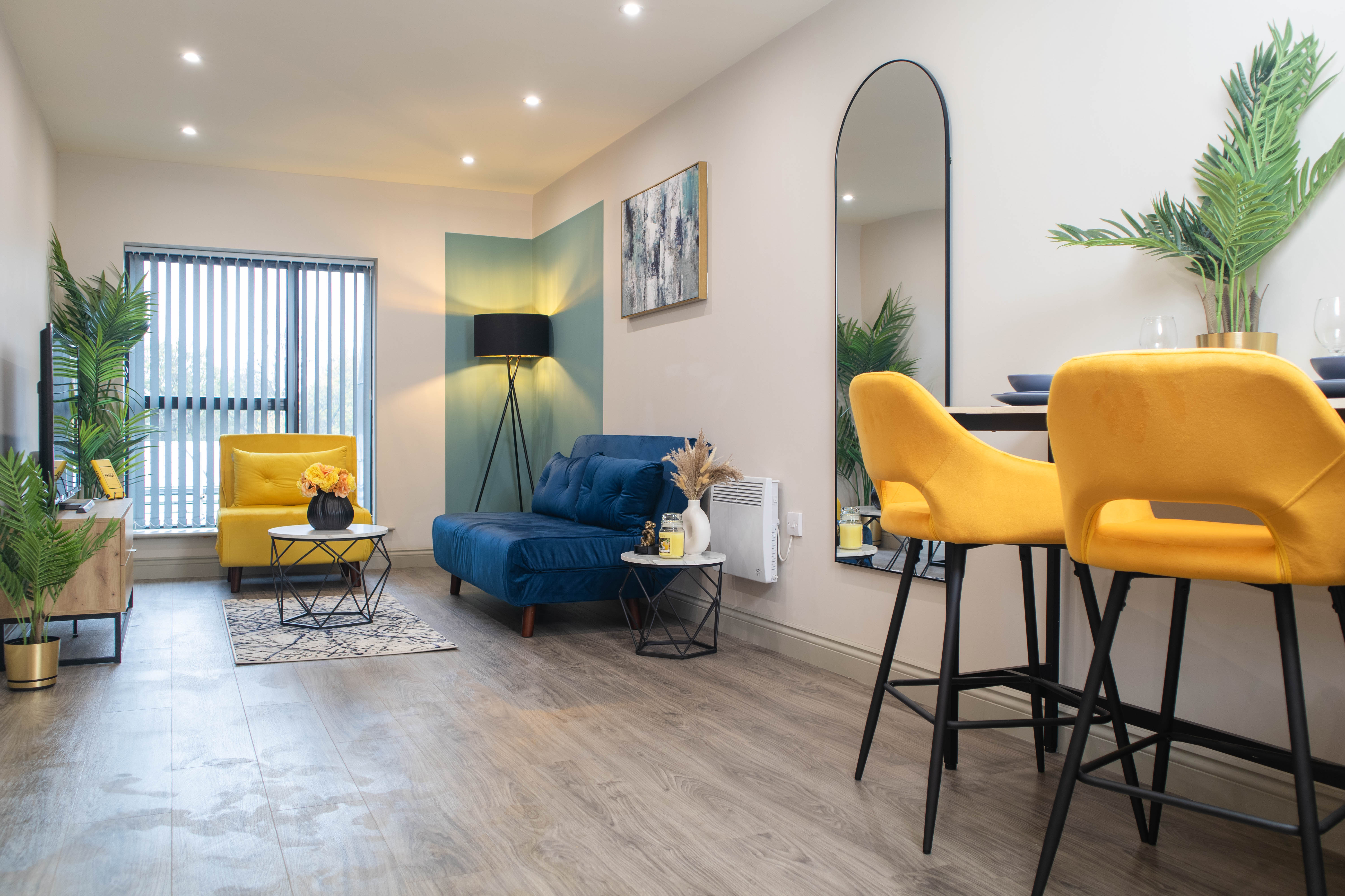 Modern open plan living room with yellow accent chairs and blue sofabed
