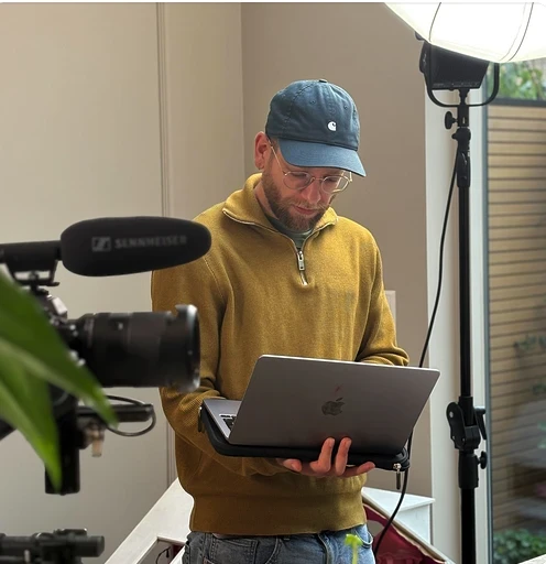 Videograaf werkt aan laptop in studio met professionele camera en verlichting