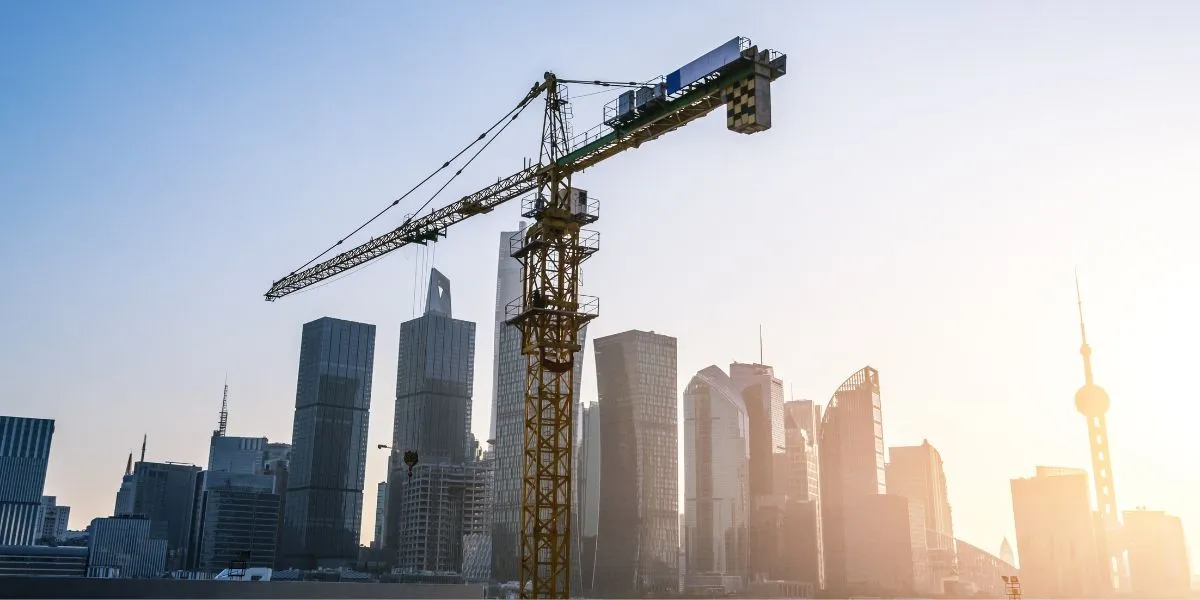 A man stands while two people sit at a table in an office setting, smiling and engaged in conversation. The mood is friendly and collaborative.