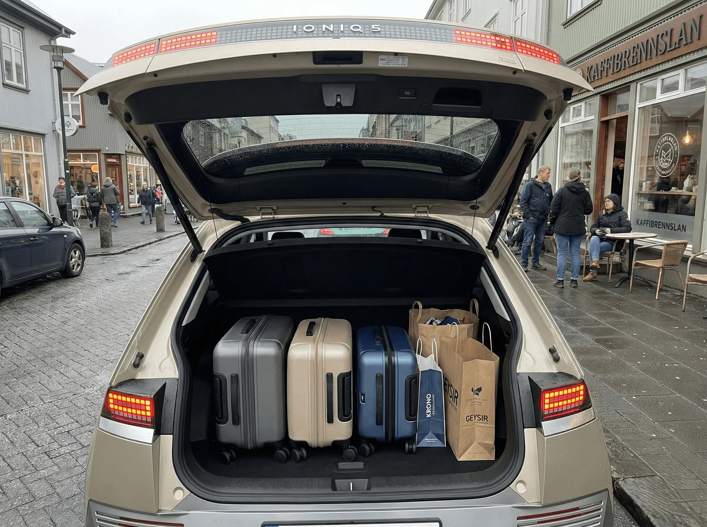 Rear view of a beige electric SUV with the trunk open, revealing it is fully packed with suitcases and bags.