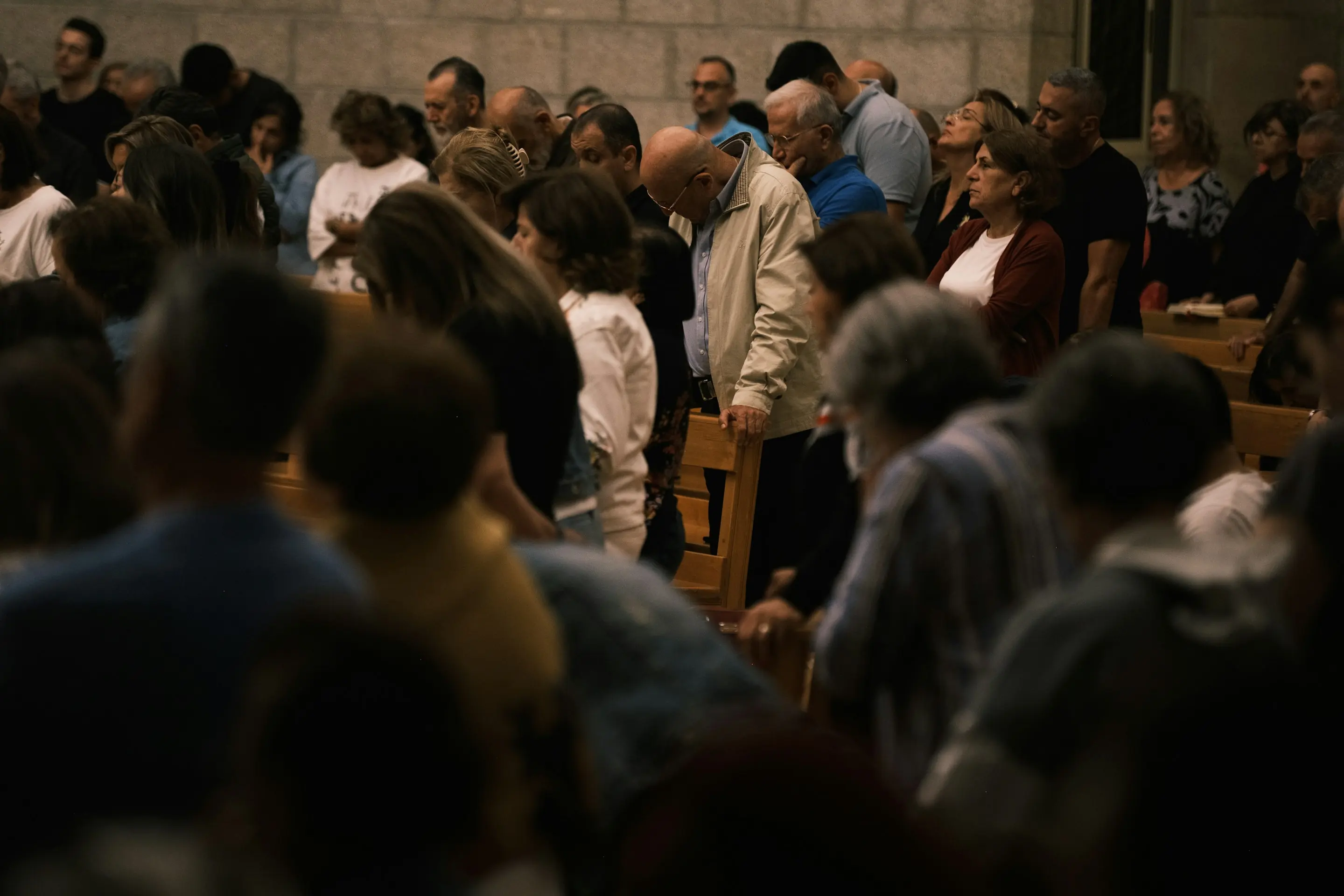 People standing with heads bowed in prayer during a gathering
