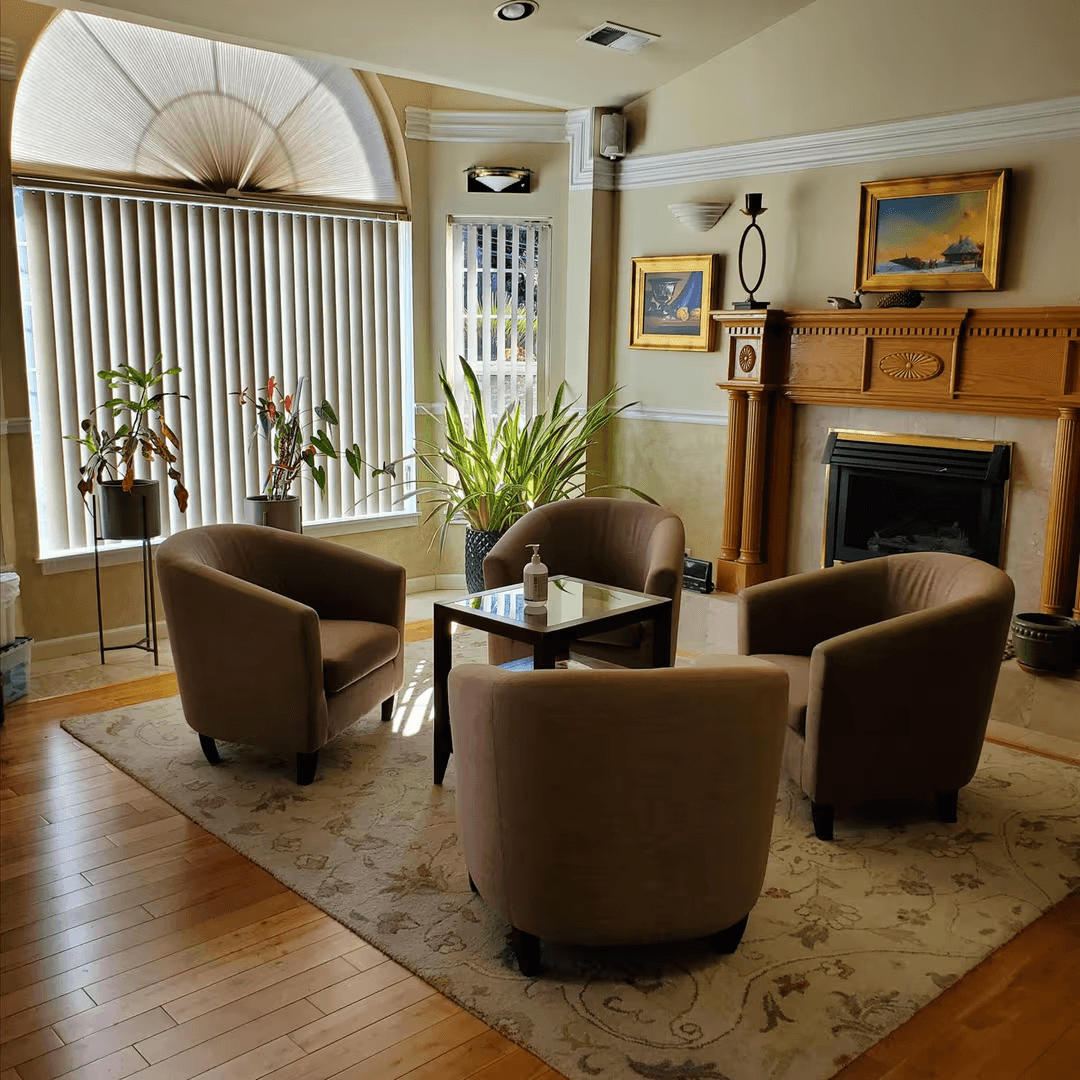 Cozy central gathering space in an adult family home with seating around a table and a fireplace for warmth and conversation.
