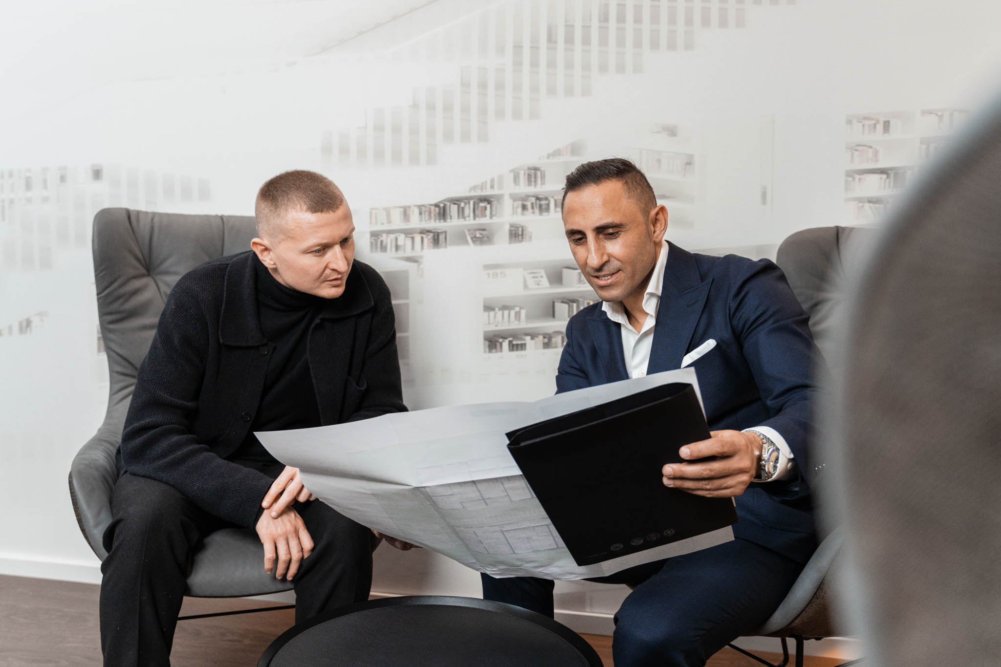 Ein Berater des Bauträgers CONCEPTGATE im entspannten Verkaufsgespräch mit einem Kundenpaar auf dem Baugrundstück in Remshalden. Im Hintergrund sind die ersten Baufortschritte und der zukünftige Hauseingang erkennbar.