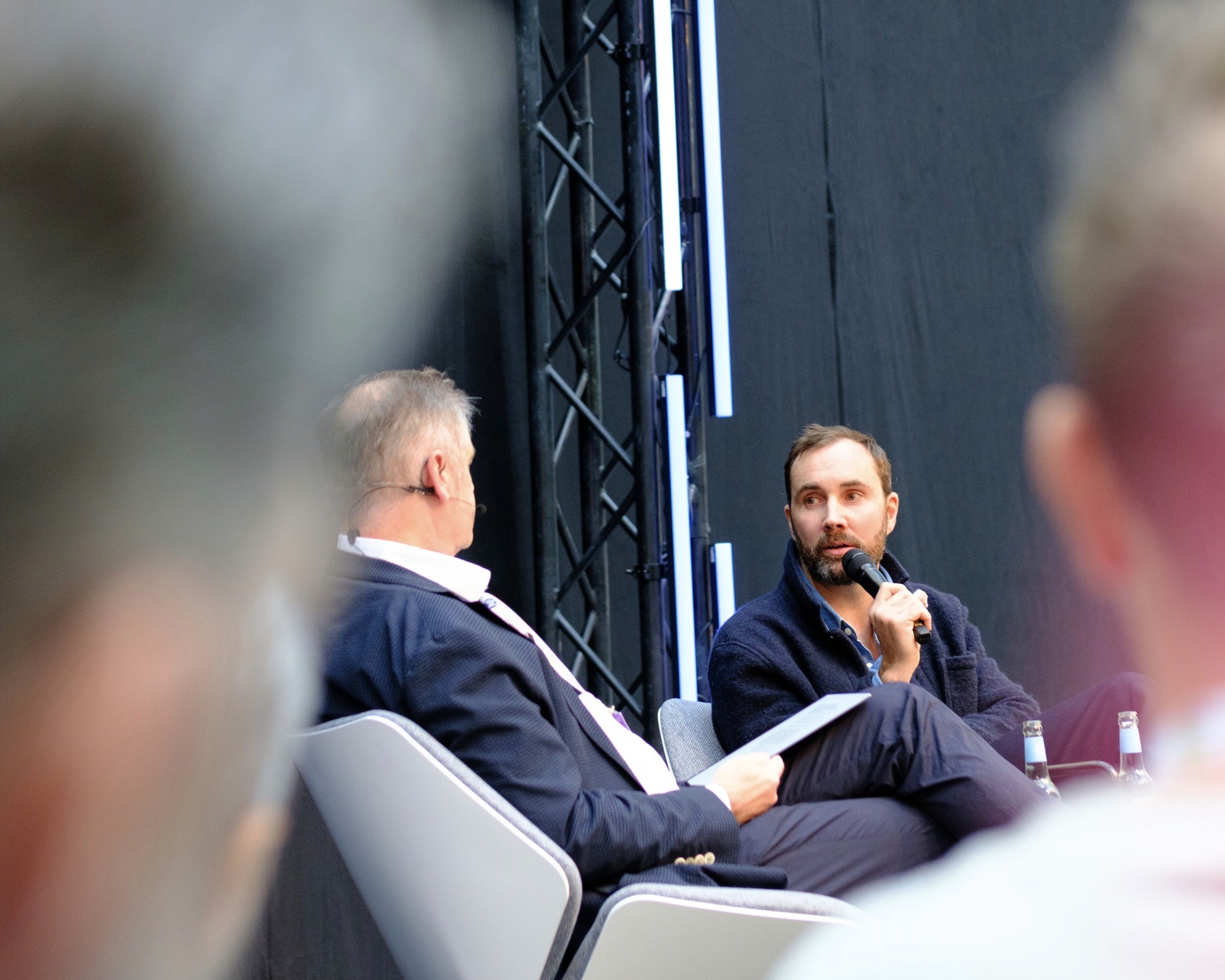 Two people talking at a table beside an open laptop