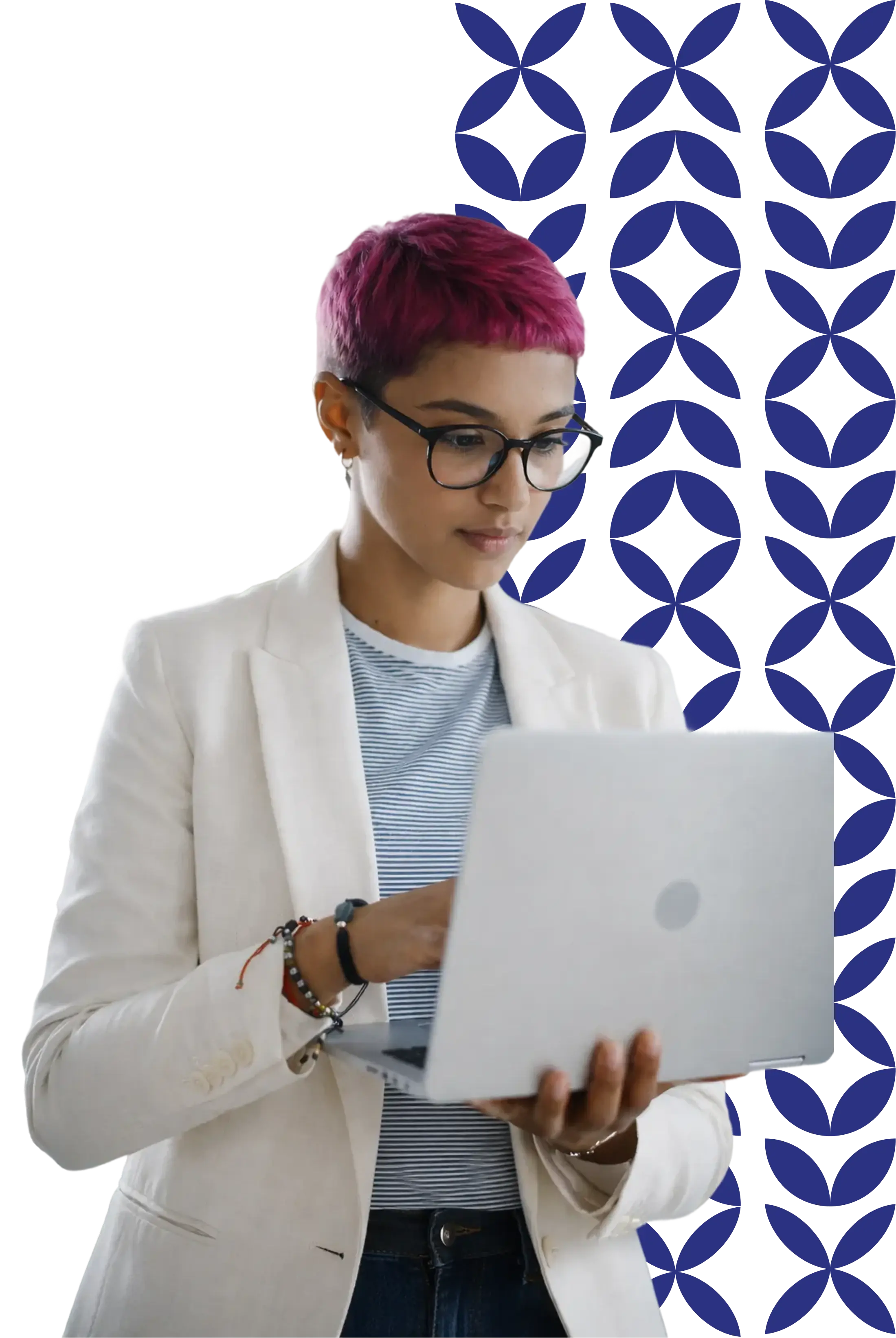 A person with short pink hair and glasses, wearing a white blazer over a striped shirt, stands focused while typing on a silver laptop, with a textured blue pattern in the background.