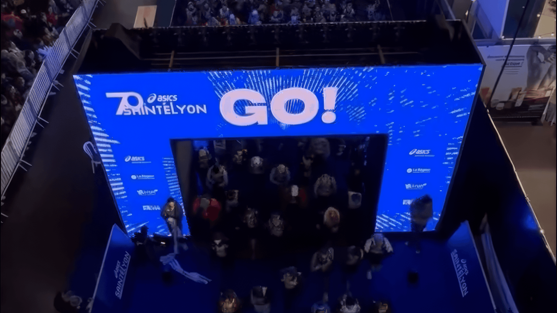 Photographie surplombant la foule de coureur traversant l'arche de départ de la Asics Saintélyon. avec l'inscription GO!