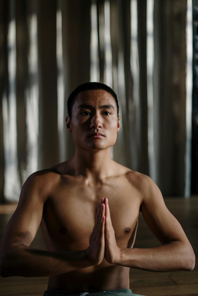 Shirtless man meditating indoors
