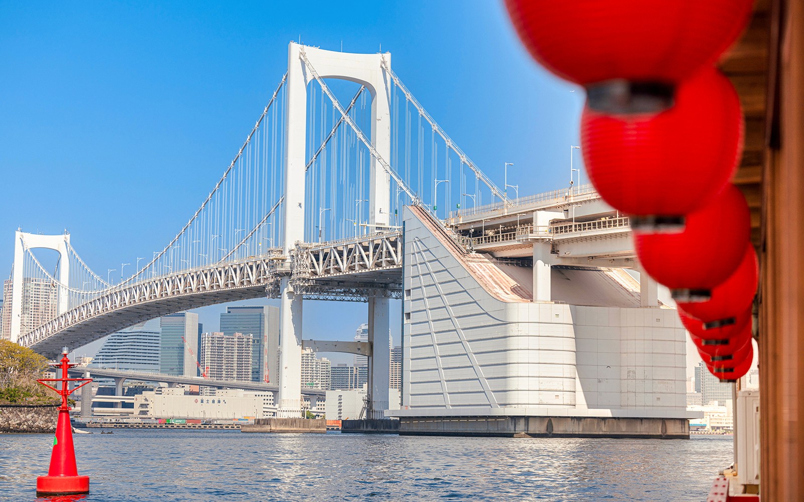 Traditional yakatabune boat cruising Tokyo Bay with city skyline in background.