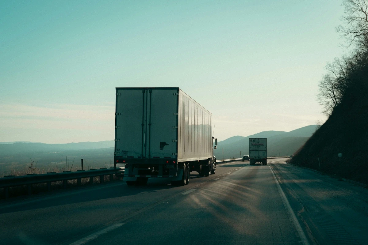 Box truck driving on a highway through the mountains, representing interstate trucking subject to FMCSA insurance requirements.