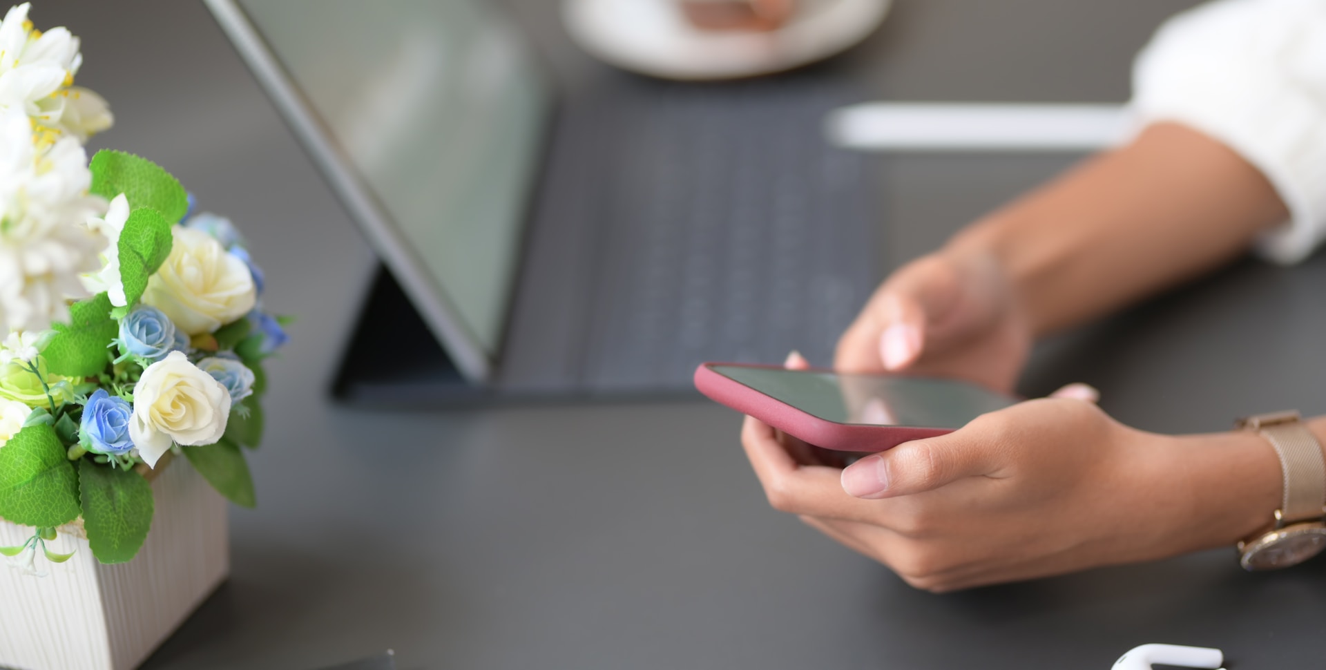 A person holding a phone white sitting on a desk