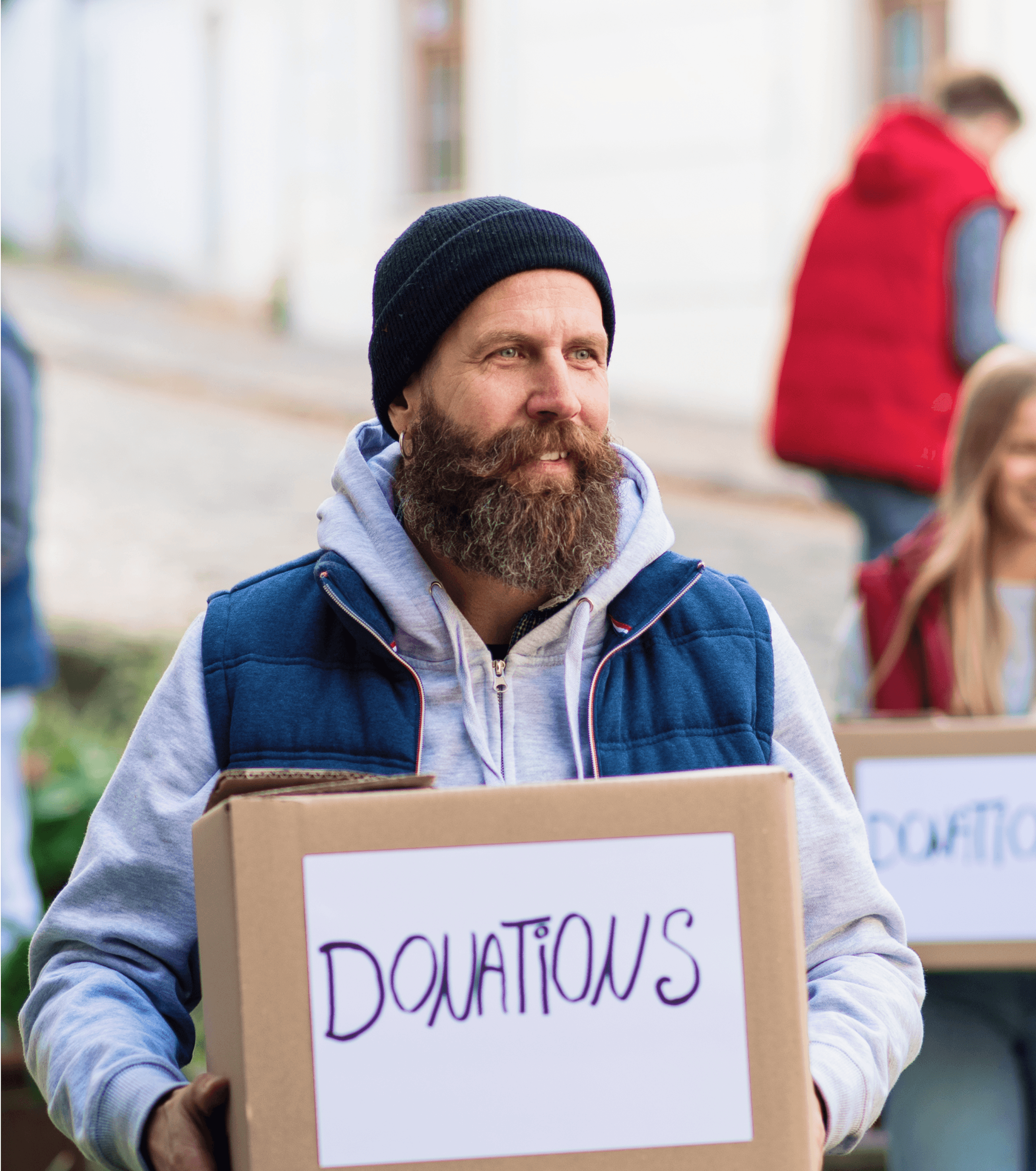 A bearded man holds a sign while participating in a demonstration, surrounded by others in a city setting.