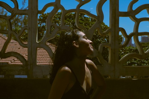 A woman lying down with a towel wrapped around her head, her face glistening with facial oil. Her eyes are closed, and she appears to be enjoying a spa treatment in a peaceful setting.