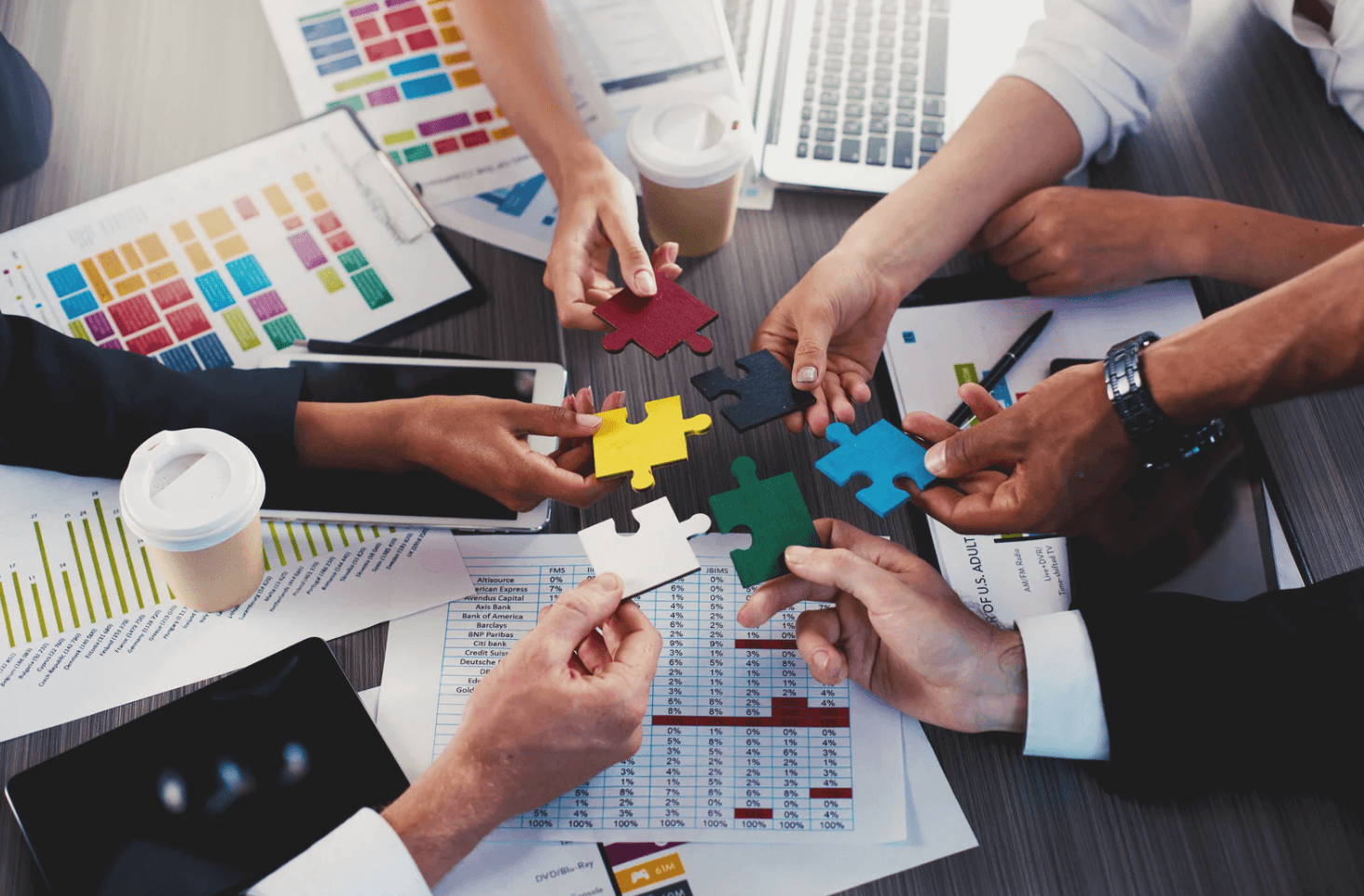 Team joining colourful puzzle pieces together over analytics reports, representing integrated Amazon ad management where all campaign types work in sync.