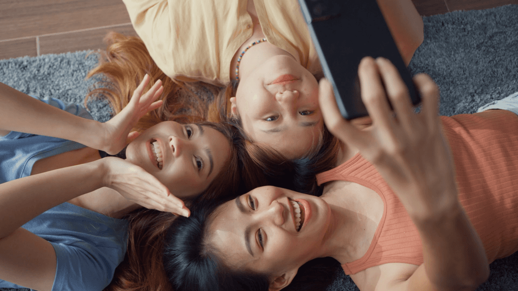 Filipina friends lying down on the ground taking a selfie