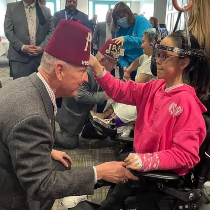 a ACCA member kneeling down to a young girl in a wheel chair