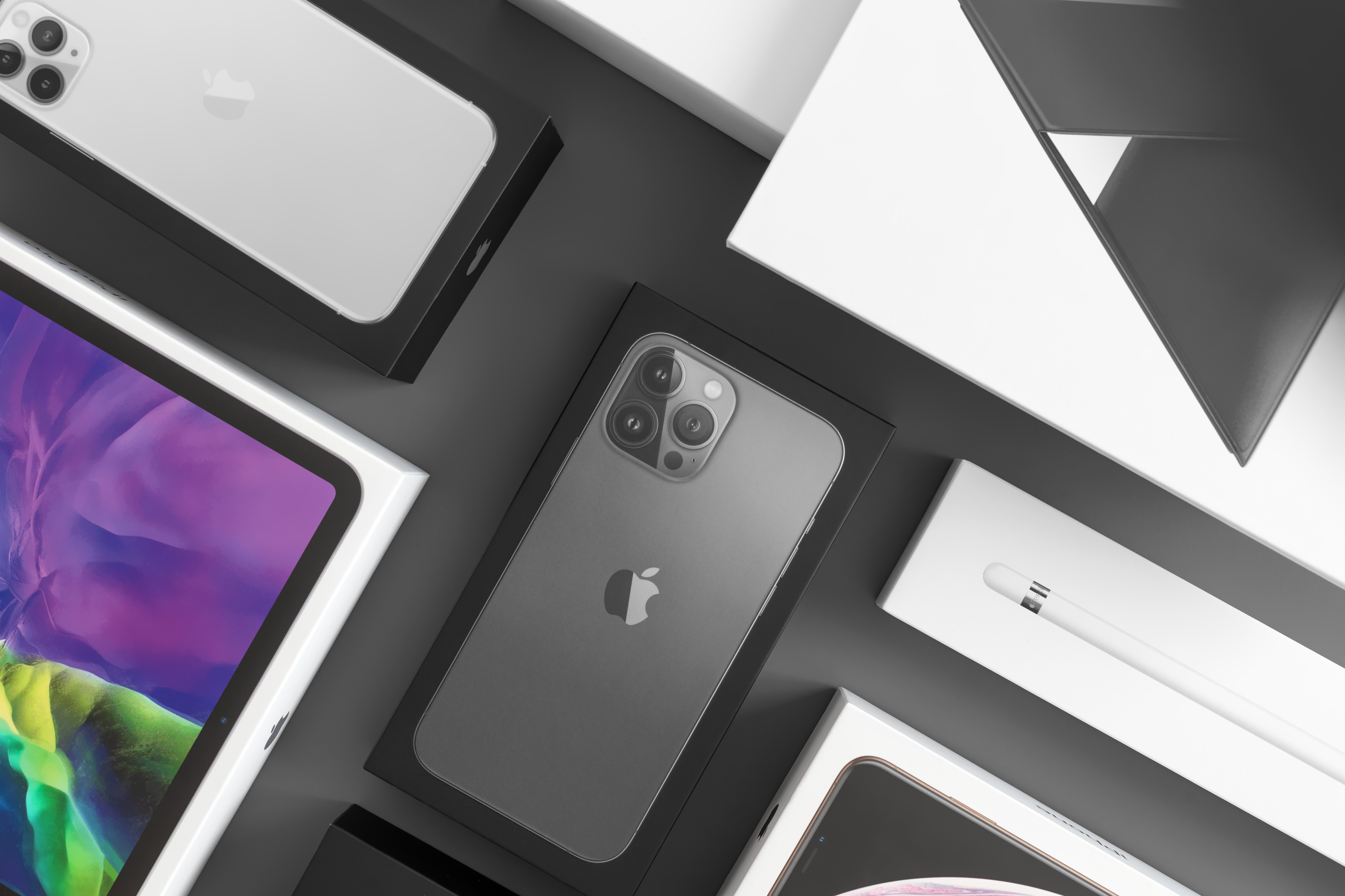 iPhone smartphone boxes: iPhones, headphones, watches are on a grey background.