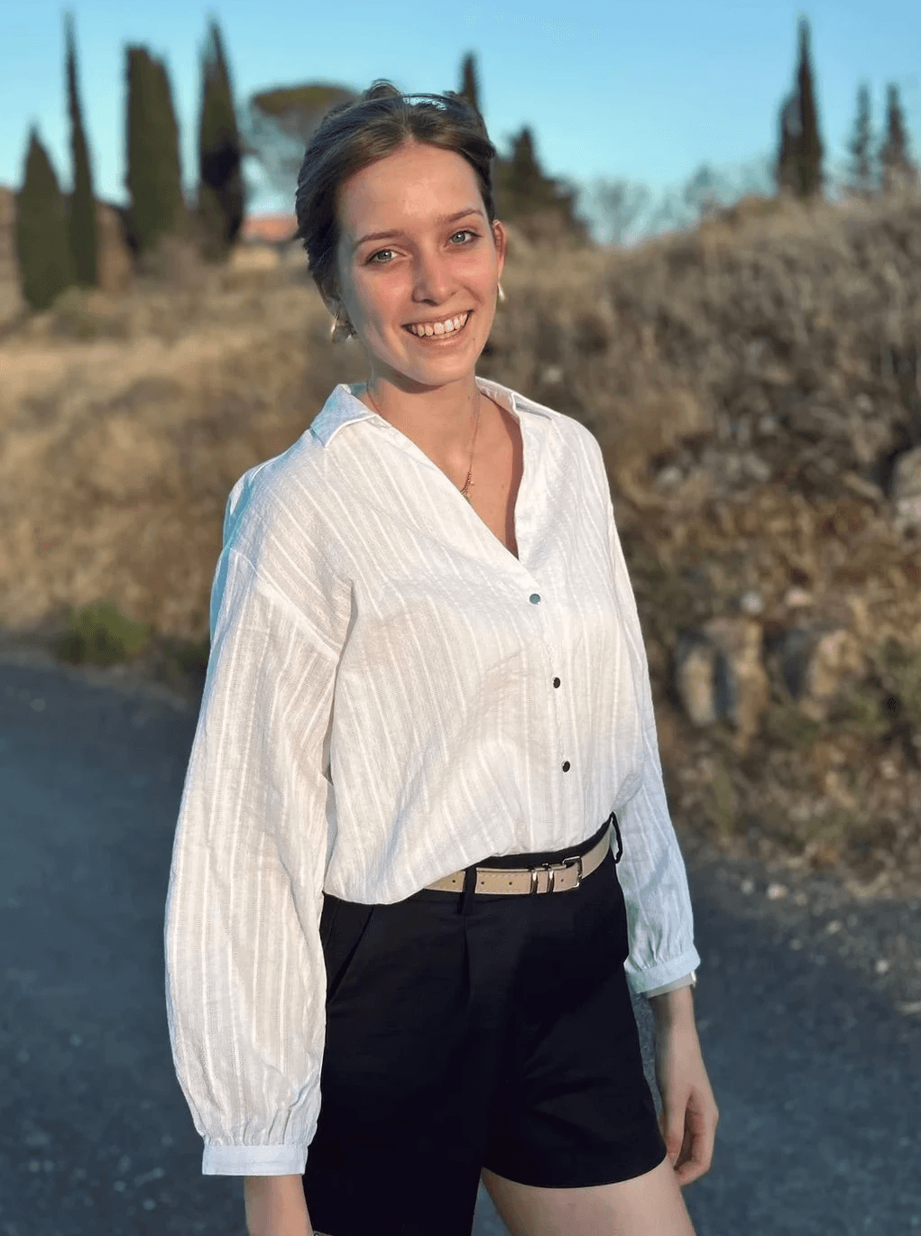 Portrait of a laughing person with curly hair wearing a white shirt