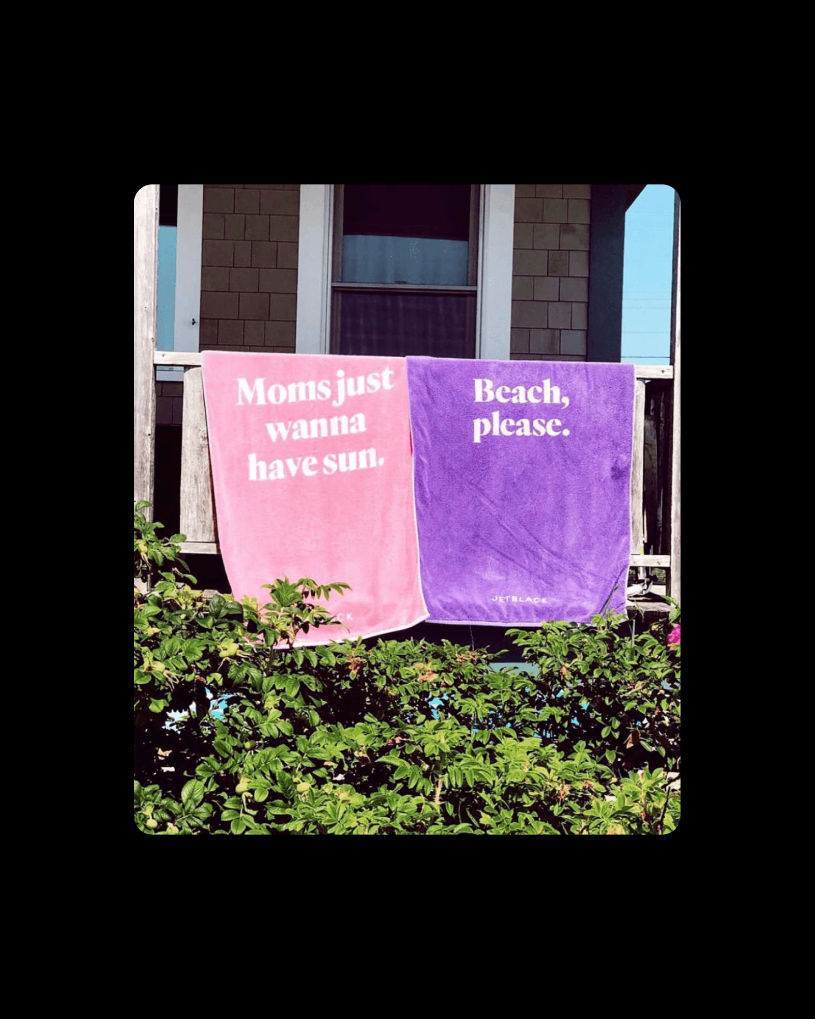 Two Jetblack beach towels, printed with playful taglines, dry on a porch railing, extending the new brand voice into merchandise.