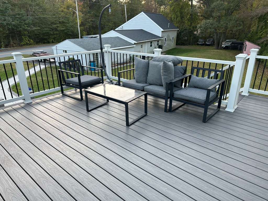 Smiling person with curly hair, wearing a black shirt, against a warm, dark background.