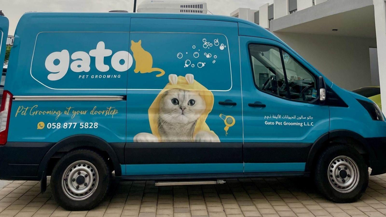 The Gato Pet Grooming van parked in an open space in front of a garage.