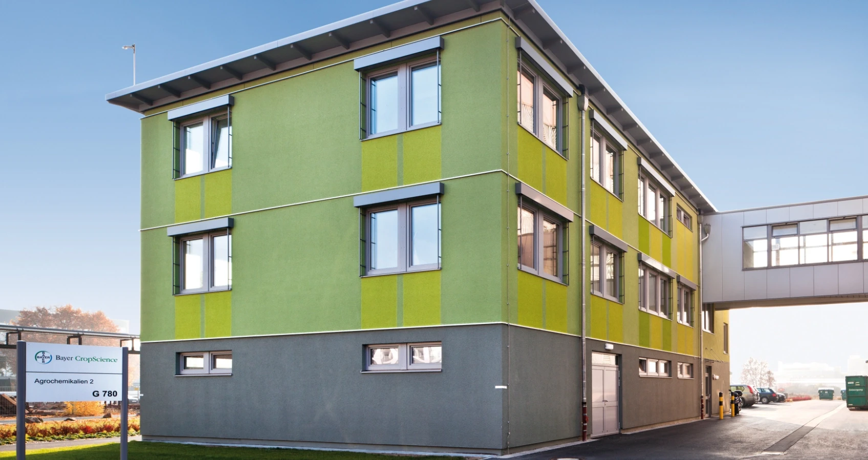 Modernes Gebäude von Bayer CropScience in Grün und Grau mit Verbindungssteg und Schild.