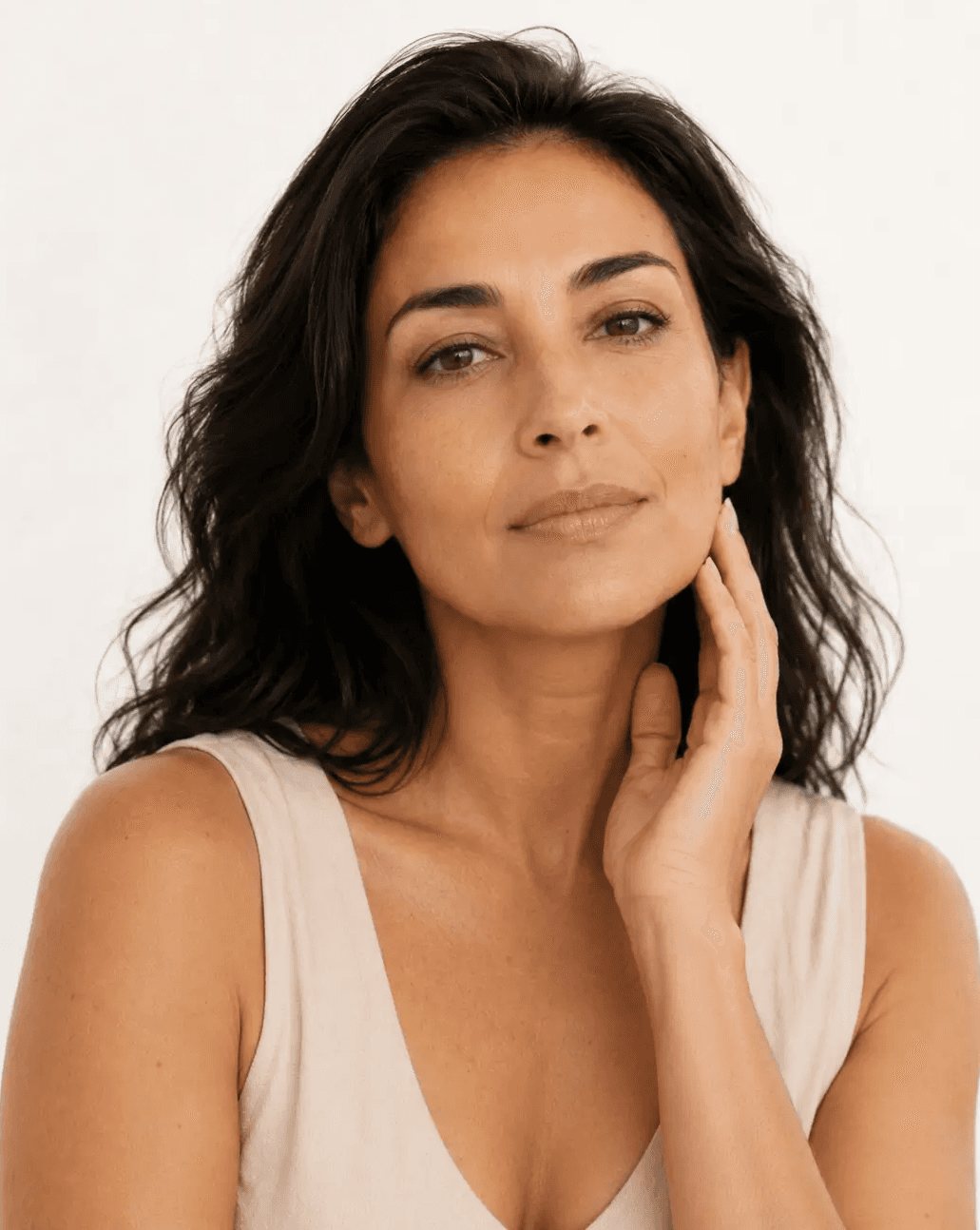 Mulher adulta de cabelos escuros com a mão próxima ao rosto e variações naturais de tonalidade na pele