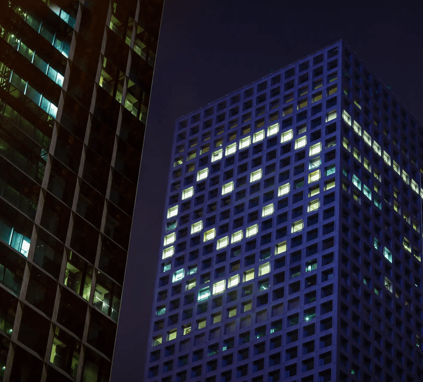 Hochhaus mit beleuchteten Fenstern in Form eines Smileys als Symbol für moderne Unternehmenswerte
