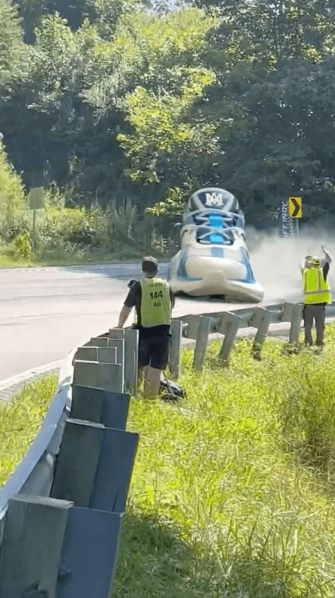A massive sneaker "driving" down a road past a stunned worker