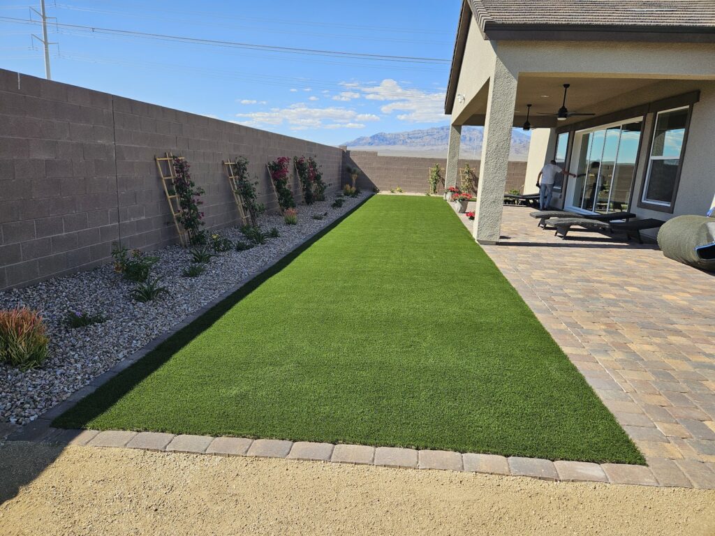 FreshStart Landscaping Vegas backyard artificial turf lawn with paver patio and decorative desert plants