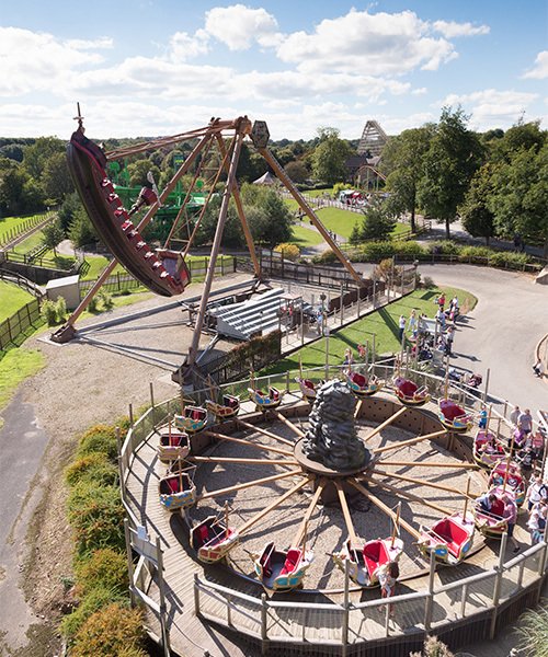 Aerial view of theme park with multiple rides and attractions surrounded by greenery