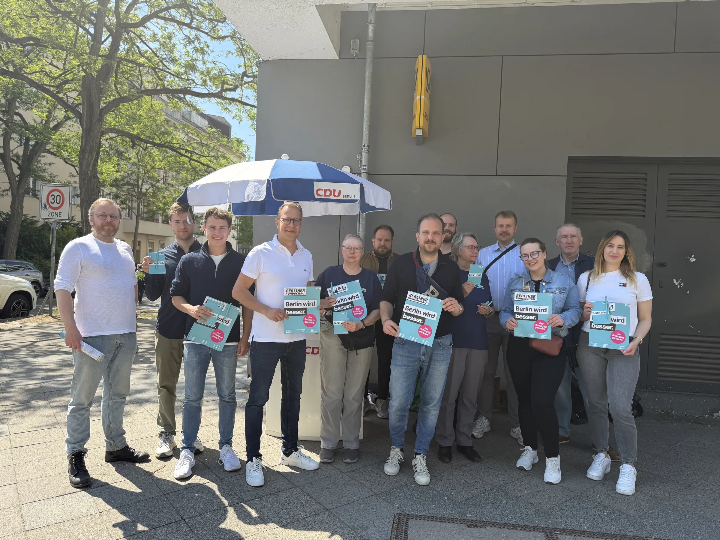 Adrian Grasse und sein Team stehen an einem sonnigen Tag an einem CDU-Infostand auf der Straße und präsentieren Wahlkampf-Flyer.