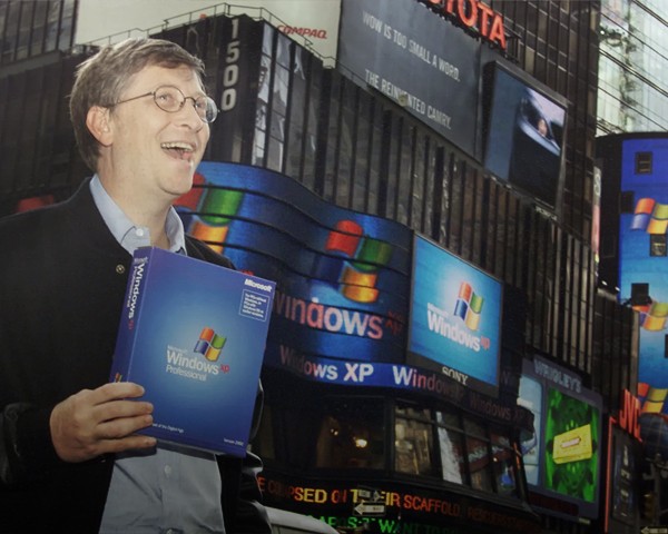 Early dot com photo of Bill Gates holding up Windows XP software in front of Windows advertisements in Times Square, New York