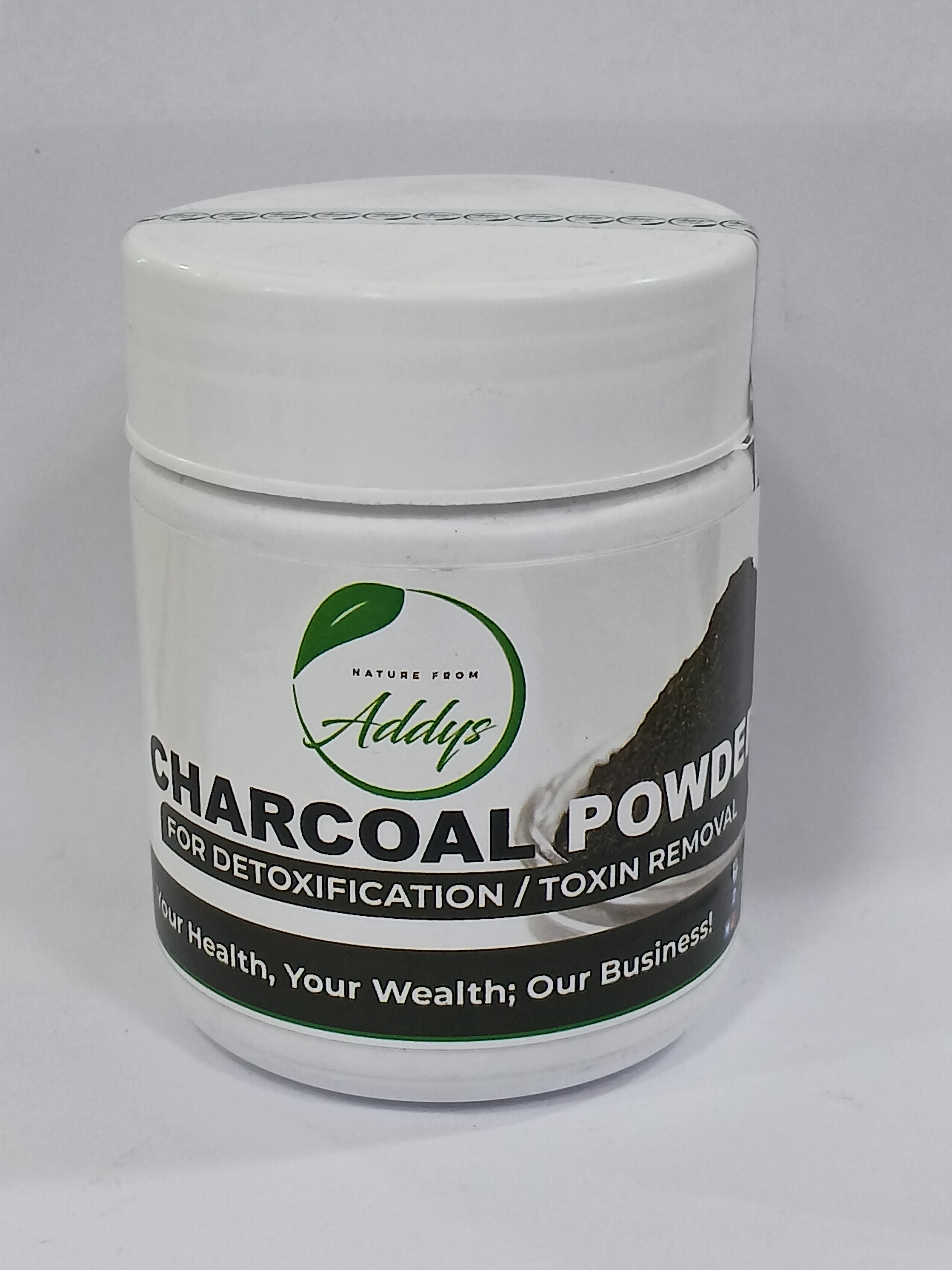 White plastic jar with a black lid and a green and black label displaying text about detoxification and toxin removal, placed on a plain light grey background.