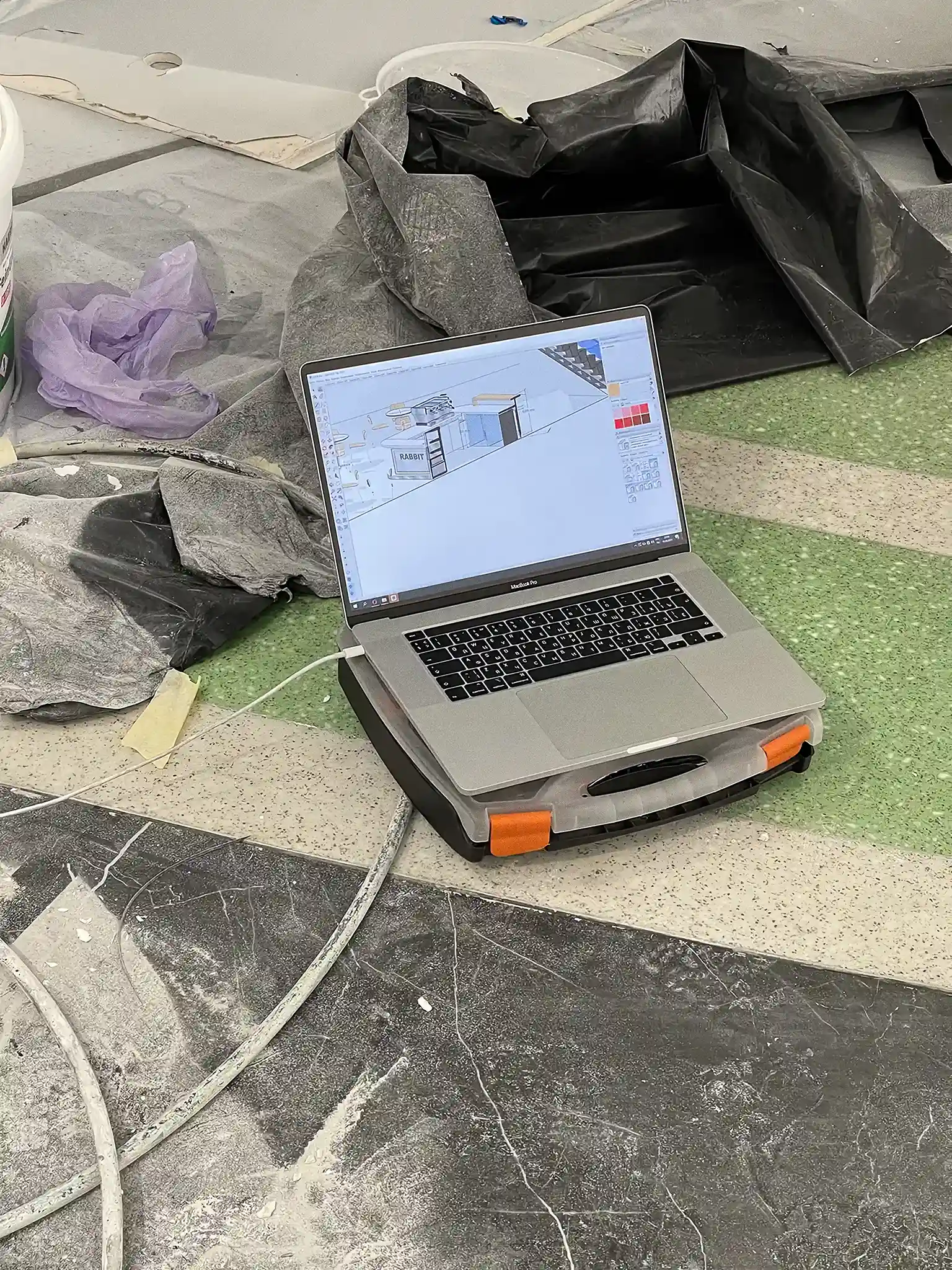 A MacBook Pro with the Rabbit Coffee Roasters SketchUp model is placed directly on site during installation. The fragment connects the digital project file with the unfinished construction space around it.